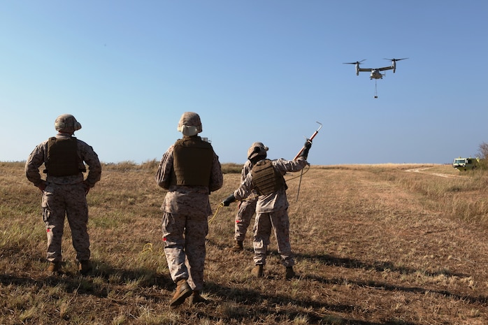 Landing support specialists wait to detach a 7,000-pound cement block from an MV-22B Osprey during dual-point external training at Ie Shima Oct. 25. The Marines supported Marine Medium Tiltrotor Squadron 265 during the training, which consisted of lifting and moving the block to different locations near the landing zone. The landing support specialists are with Combat Logistics Regiment 37, 3rd Marine Logistics Group, III Marine Expeditionary Force. The pilot and crew are with VMM-265, 1st Marine Aircraft Wing, III MEF. 