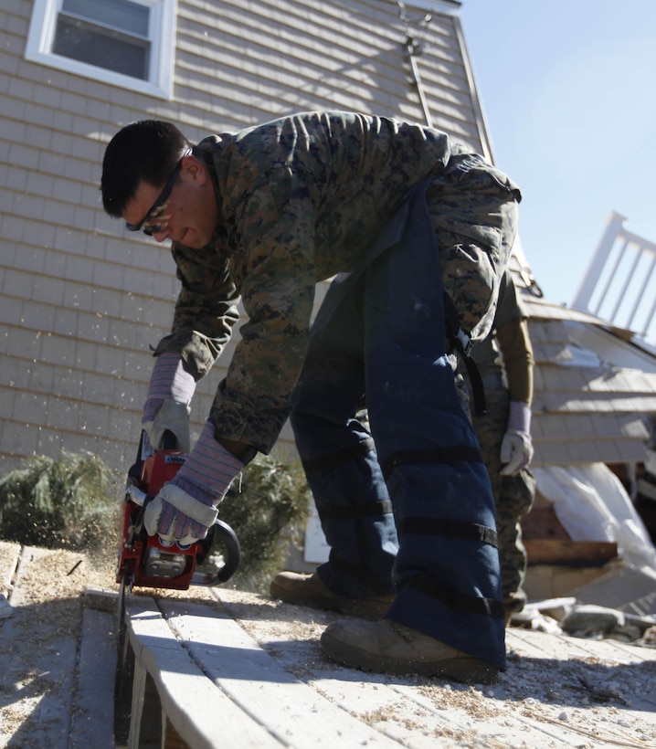 Lance Cpl. Phillip Clonch, a combat engineer with 8th Engineer Support Battalion, 2nd Marine Logistics Group cuts a deck into smaller pieces using a chainsaw in Breezy Point, N.Y., Nov. 6. The Marines were moving debris in the neighborhood in support of humanitarian operations with the Federal Emergency Management Agency after Hurricane Sandy.
