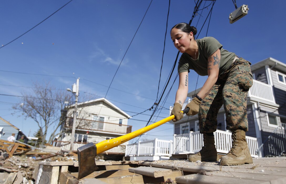 Cpl. Chelsea Thomas, a radio operator with 8th Engineer Support Battalion, 2nd Marine Logistics Group uses an axe to break down a large deck in order to clear a walkway for residents to safely into Breezy Point, N.Y., Nov. 6. The Marines were moving debris in the neighborhood in support of humanitarian operations with the Federal Emergency Management Agency after Hurricane Sandy.