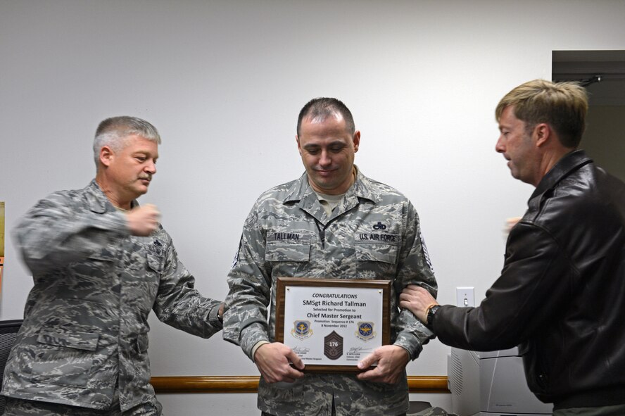 Col. Wyn Elder (right), 62nd Airlift Wing commander, and Chief Master Sgt. Gordon Drake, 62nd AW command chief, tack chief master sergeant stripes on Senior Master Sgt. Richard Tallman (center), 62nd Comptroller Squadron superintendent, Nov. 8, 2012, at Joint Base Lewis-McChord, Wash. Tallman was surprised by McChord Field leadership and 14 chief master sergeants when he received his line number of 176. (U.S. Air Force photo/Staff Sgt. Frances Kriss)