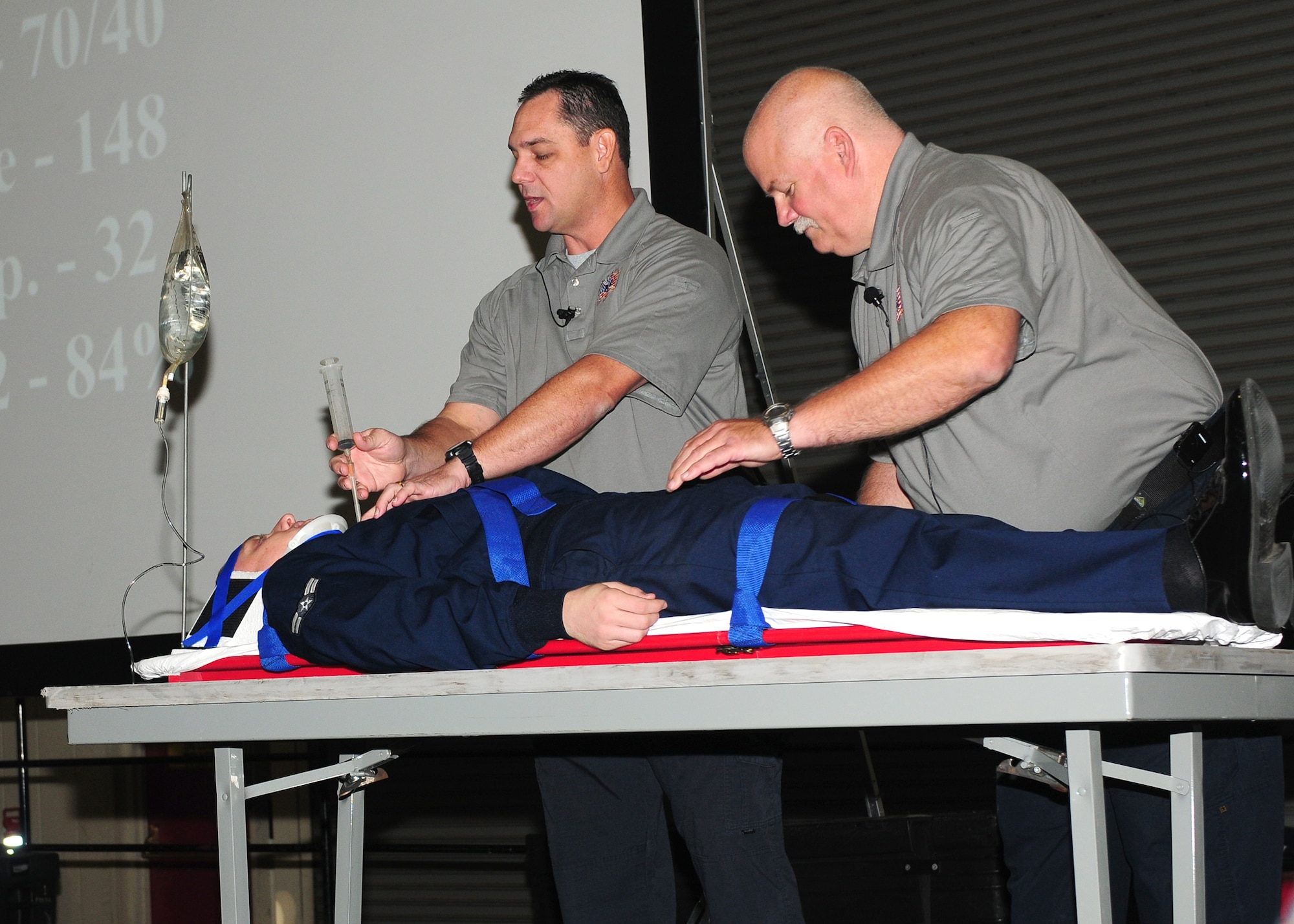 Scott Neusch (left) and Greg McCarty (right) both Fla. fire department paramedics demonstrate how to relieve a collapsed lung on Airman 1st Class Zachary Lessley, 9th Communication Squadron knowledge operations manager. The demonstration showed steps needed to stabilize a victim. (U.S. Air Force photo by Senior Airman Allen Pollard)