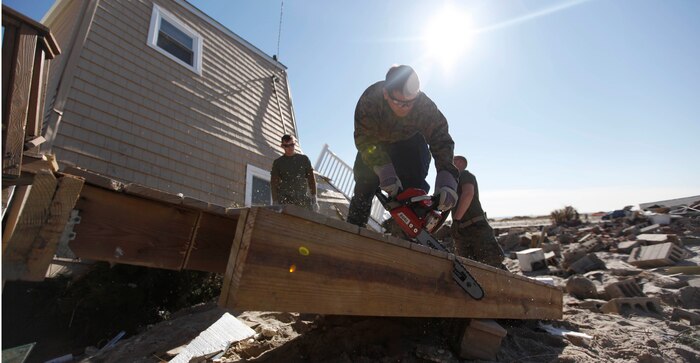 Lance Cpl. Phillip Clonch, a combat engineer with 8th Engineer Support Battalion, 2nd Marine Logistics Group cuts a deck into smaller pieces using a chainsaw in Breezy Point, N.Y., Nov. 6. The Marines were moving debris in the neighborhood in support of humanitarian operations with the Federal Emergency Management Agency after Hurricane Sandy.