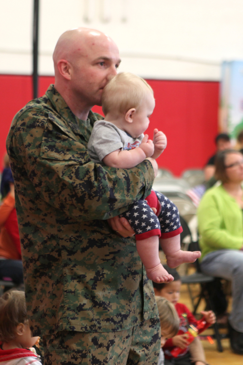 Gunnery Sgt. Justin Cooke, an air traffic controller with Headquarters and Headquarters Squadron, holds his son, Steel, for a better view of The Sesame Street/ USO Experience for Military Families at Marine Corps Air Station Beaufort's fitness center, Nov. 6. The exclusive live performance feautured characters from Sesame Street to help children relate and cope with the challenges that coincide military lifestyle.