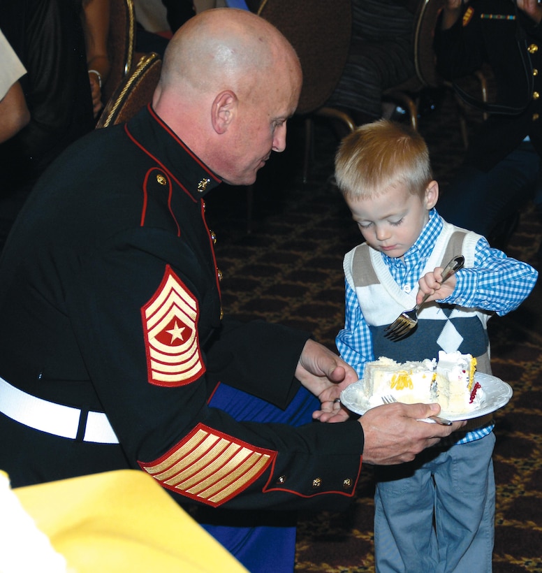 Sgt. Maj. Joseph M. Davenport, sergeant major, Marine Corps Logistics Command, the oldest Marine present at the Kids' Marine Corps Birthday Ball at Marine Corps Logistics Base Albany, passes a slice of cake to the youngest child, Louis Mixa, 2, during a cake-cutting ceremony, Nov. 3. Louis Mixa is the son of Maj. Matthew Mixa, action officer, MCLC. About 150 people attended the first-time event at the Town and Country Restaurant's Grand Ballroom.