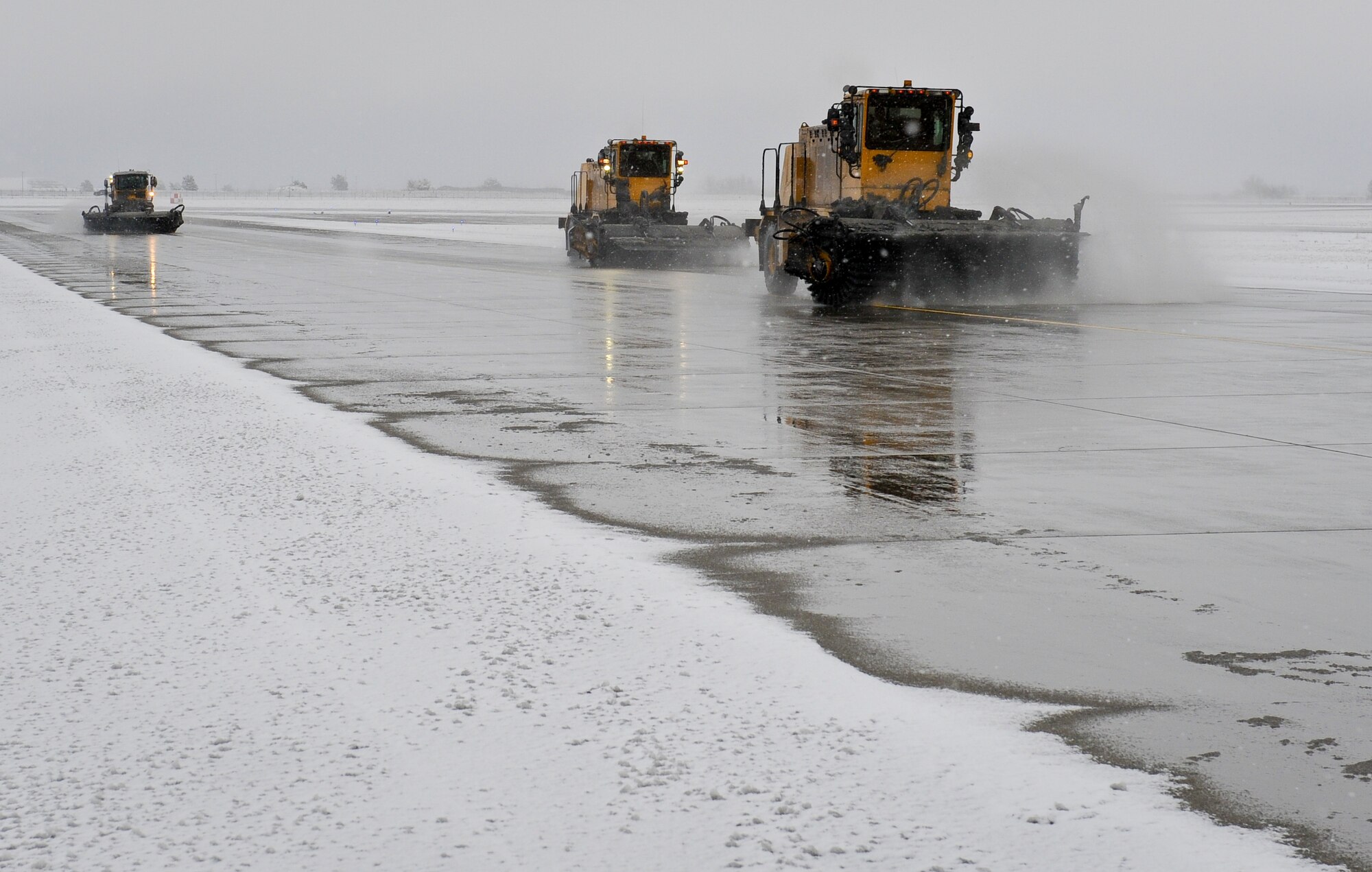 Senior Airman Steven Lowe sweeps the runway using his snow broom at Fairchild Air Force Base, Wash., Nov. 9, 2012. Lower is followed in formation by Staff Sgt. Adam Haines and Senior Airman Andrew Hamm. Fairchild’s first snow fall of the year came on the eve of Nov. 8 amassing more than three inches of snow. Lowe, Haines and Hamm are all 92nd Civil Engineer Squadron pavement and equipment operators. (U.S. Air Force photo by Senior Airman Benjamin Stratton)