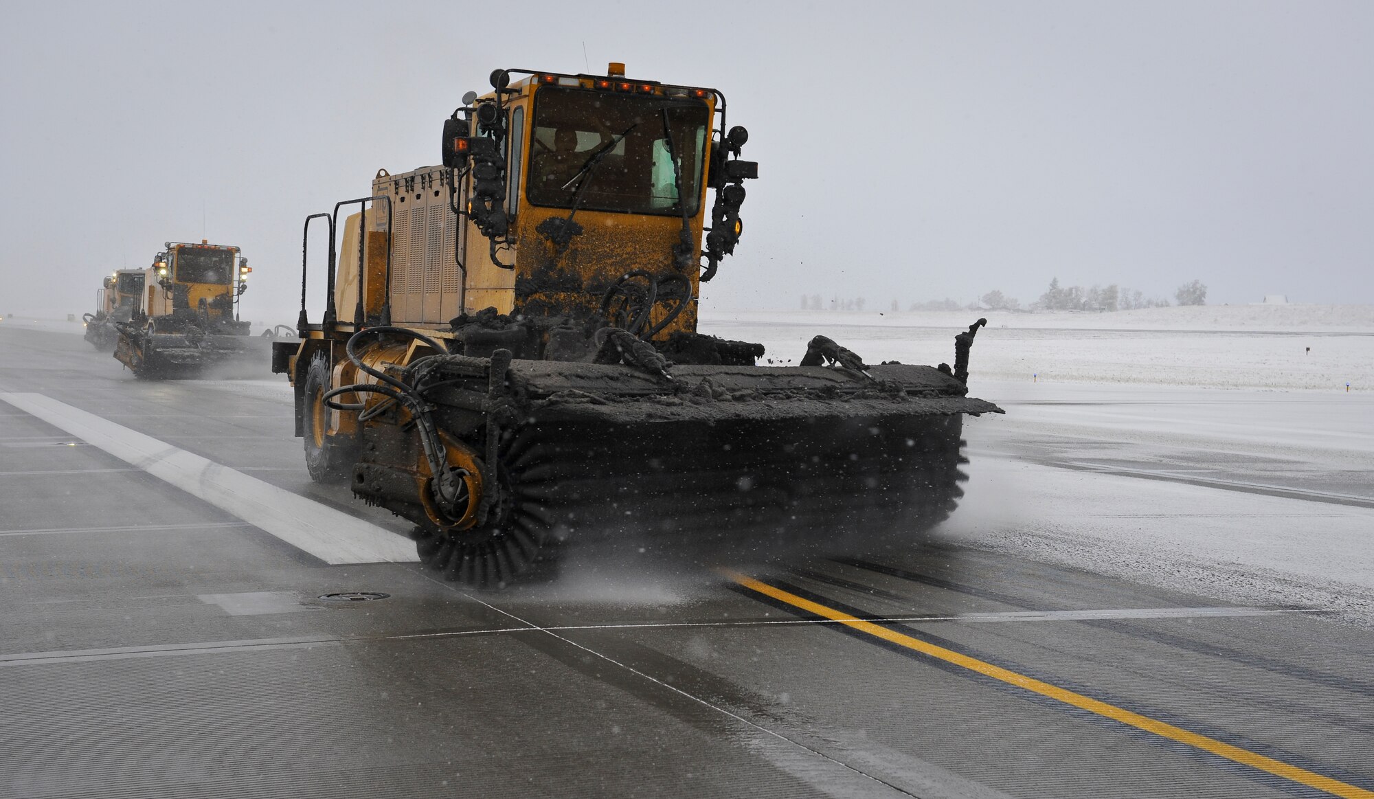 Senior Airman Steven Lowe sweeps the runway using his snow broom at Fairchild Air Force Base, Wash., Nov. 9, 2012. Lower is followed in formation by Staff Sgt. Adam Haines and Senior Airman Andrew Hamm. Fairchild’s first snow fall of the year came on the eve of Nov. 8 amassing more than three inches of snow. Lowe, Haines and Hamm are all 92nd Civil Engineer Squadron pavement and equipment operators. (U.S. Air Force photo by Senior Airman Benjamin Stratton)