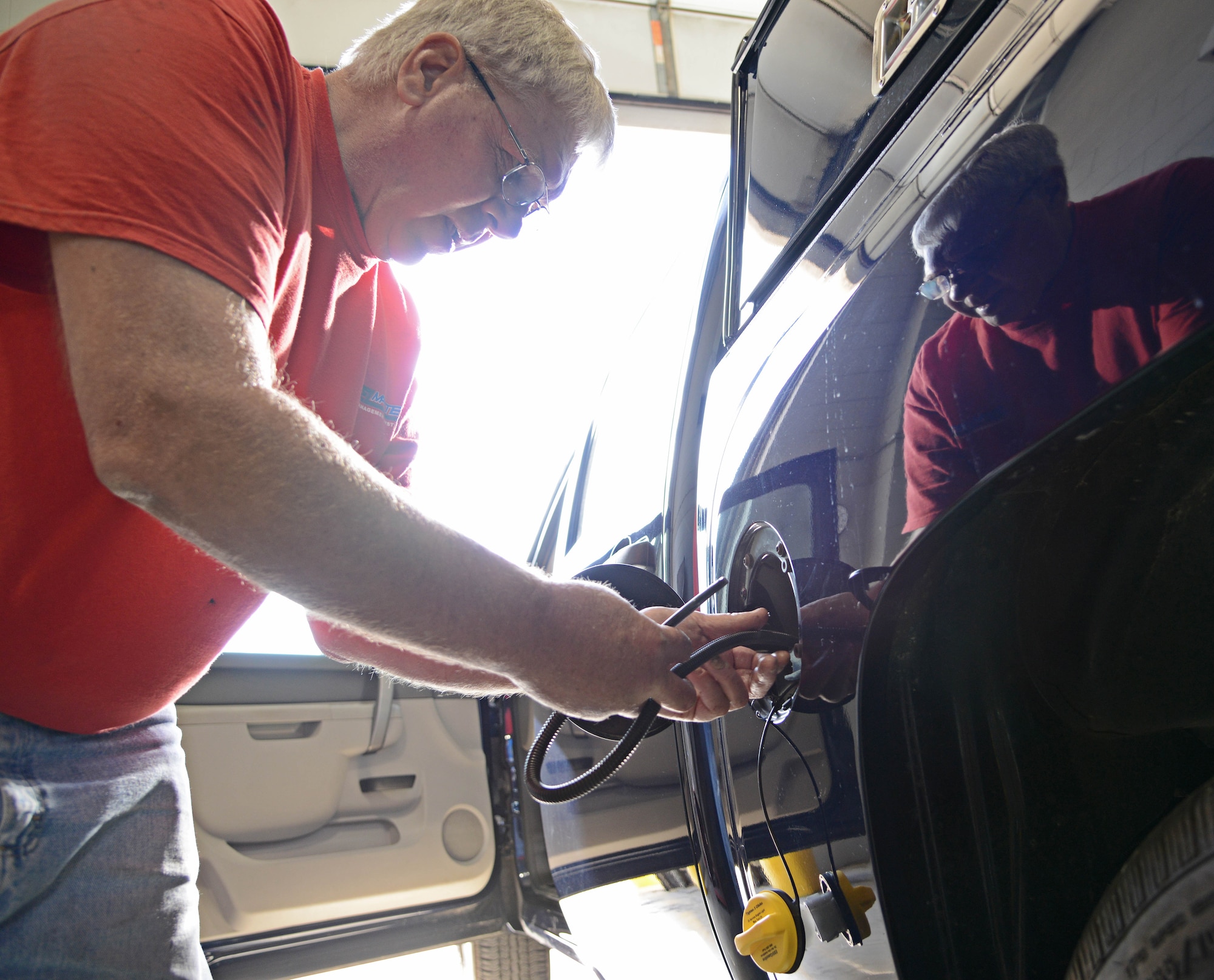 Jim Muir, 902nd Vehicle Management Flight site manager, installs the AIM2 fuel conservation system, Oct. 25 at Joint Base San Antonio-Randolph. (U.S. Air Force photo by Benjamin Faske)