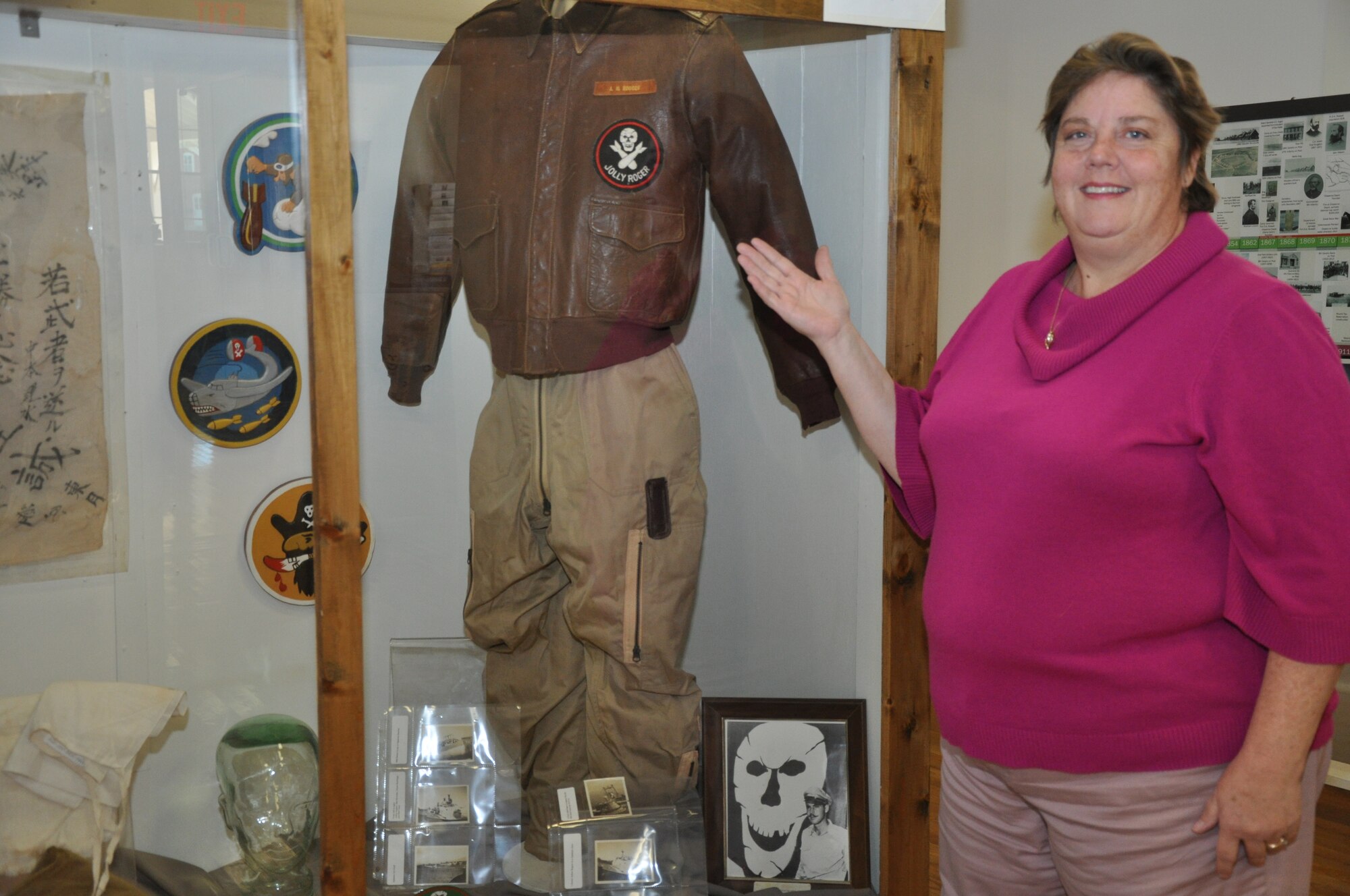 Paula Taylor, 90th Missile Wing museum curator, presents the flight jacket of Col. Art Rogers, 90th Bombardment Group commander and inspiration for the Jolly Rogers, on display in the 90th MW museum Nov. 6. The jacket is on display with a photo of Col. Rogers standing next to the “skull and cross-bombs,” along with the original patches from the 319th, 320th and 321st Bombardment Squadrons. (U.S. Air Force photo by Senior Airman Dan Gage)