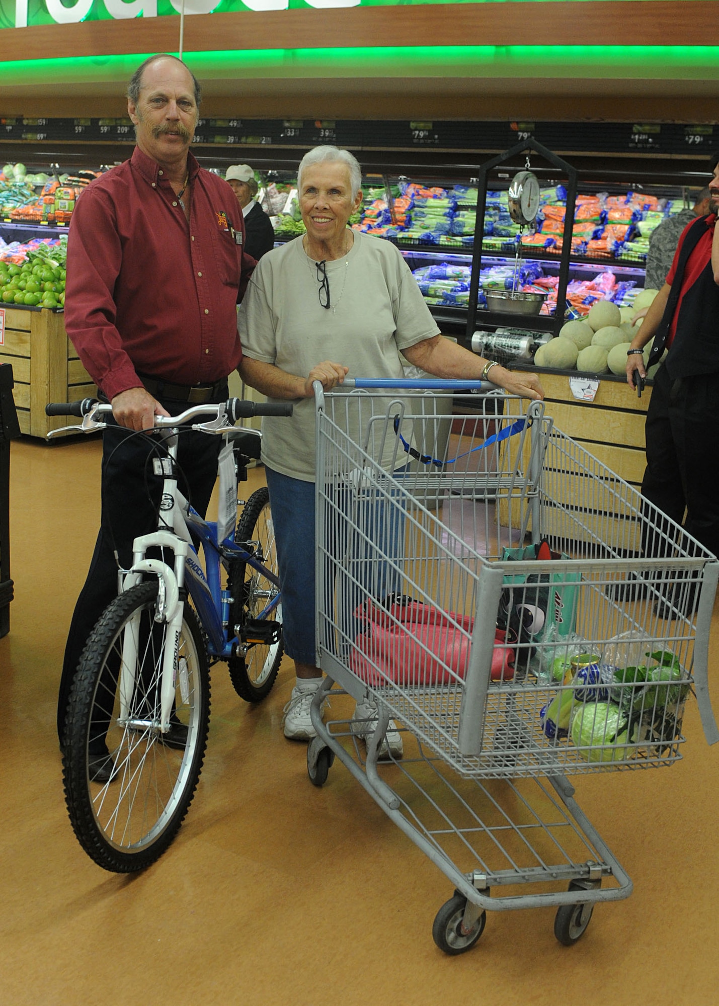 Gerry Hunt, civilian, receives her raffle prize of a new bike from Spike Lewis, grocery manager, Nov. 1 during the celebration. The event featured live music, special giveaways, and many other activities to keep the attendees entertained and to celebrate the renovations. (U.S. Air Force photo by Airman 1st Class Devante Williams)