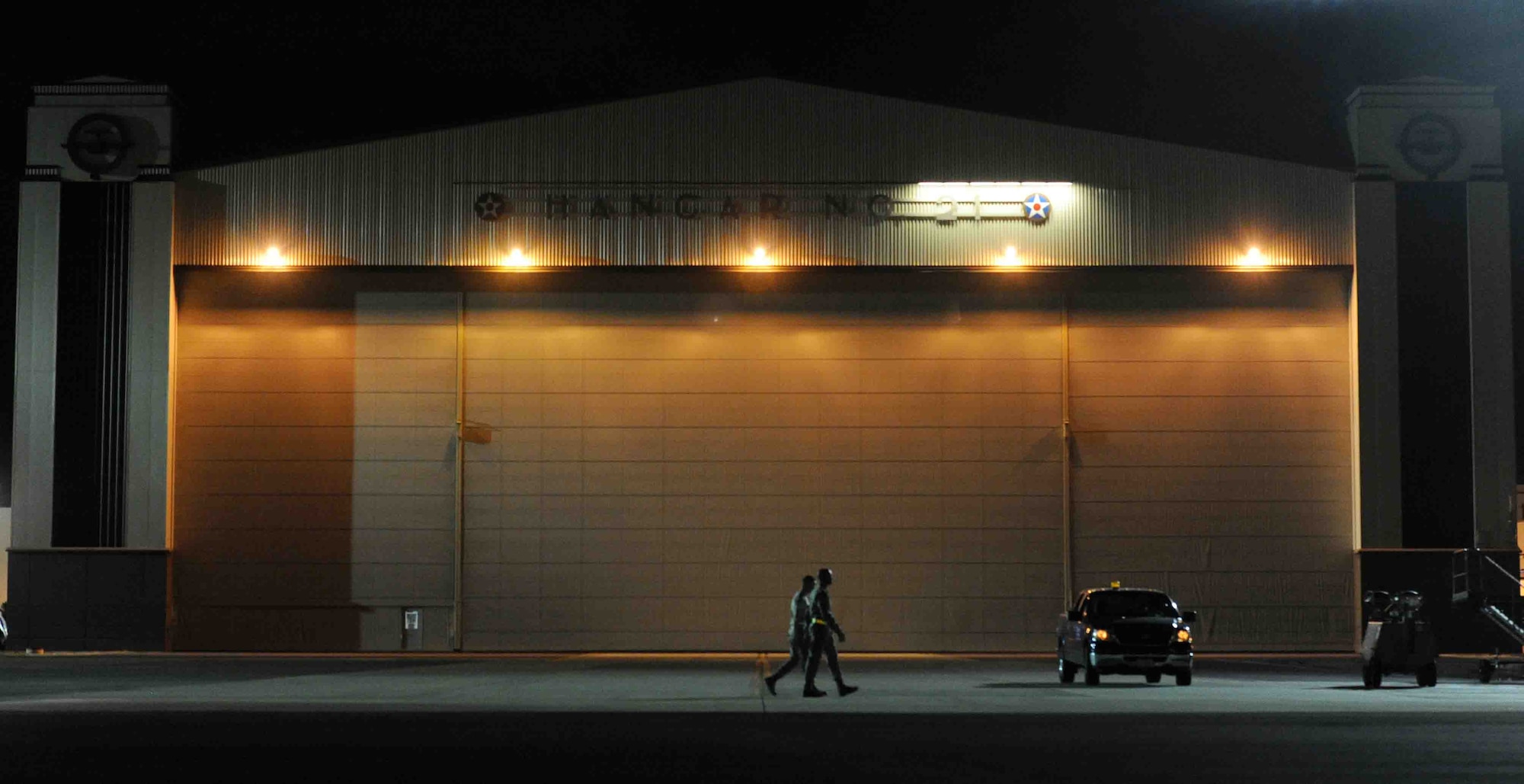 Airmen from the 735th Air Mobility Squadron walk in front of Hangar 21 at Joint Base Pearl Harbor-Hickam, Hawaii, before performing a "live load" on a C-17 Globemaster III Nov. 9. As part of a Phase I deployment exercise, the live load  simulated one step in a deployment process designed to rapidly deploy Airmen in response to worldwide contingency operations. (U.S. Air Force photo by Staff Sgt. Nathan Allen)