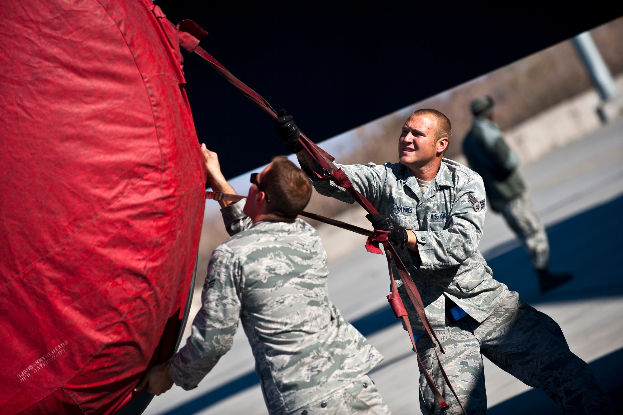 Left, Airman 1st Class Charles Melendez and Senior Airman Cody Haynes tighten a protective cover on a KC-135 Stratotanker engine at the Transit Center at Manas, Kyrgyzstan, Nov. 8, 2012.  The cover protects the engines from debris or foreign objects. Both Melendez and Haynes are 376th Expeditionary Aircraft Maintenance Squadron crew chiefs who are deployed from Fairchild Air Force Base, Wash. Melendez is a native of San Juan, Puerto Rico and Haynes is a native of Woodbridge, Va. (U.S. Air Force photo/Senior Airman Brett Clashman)