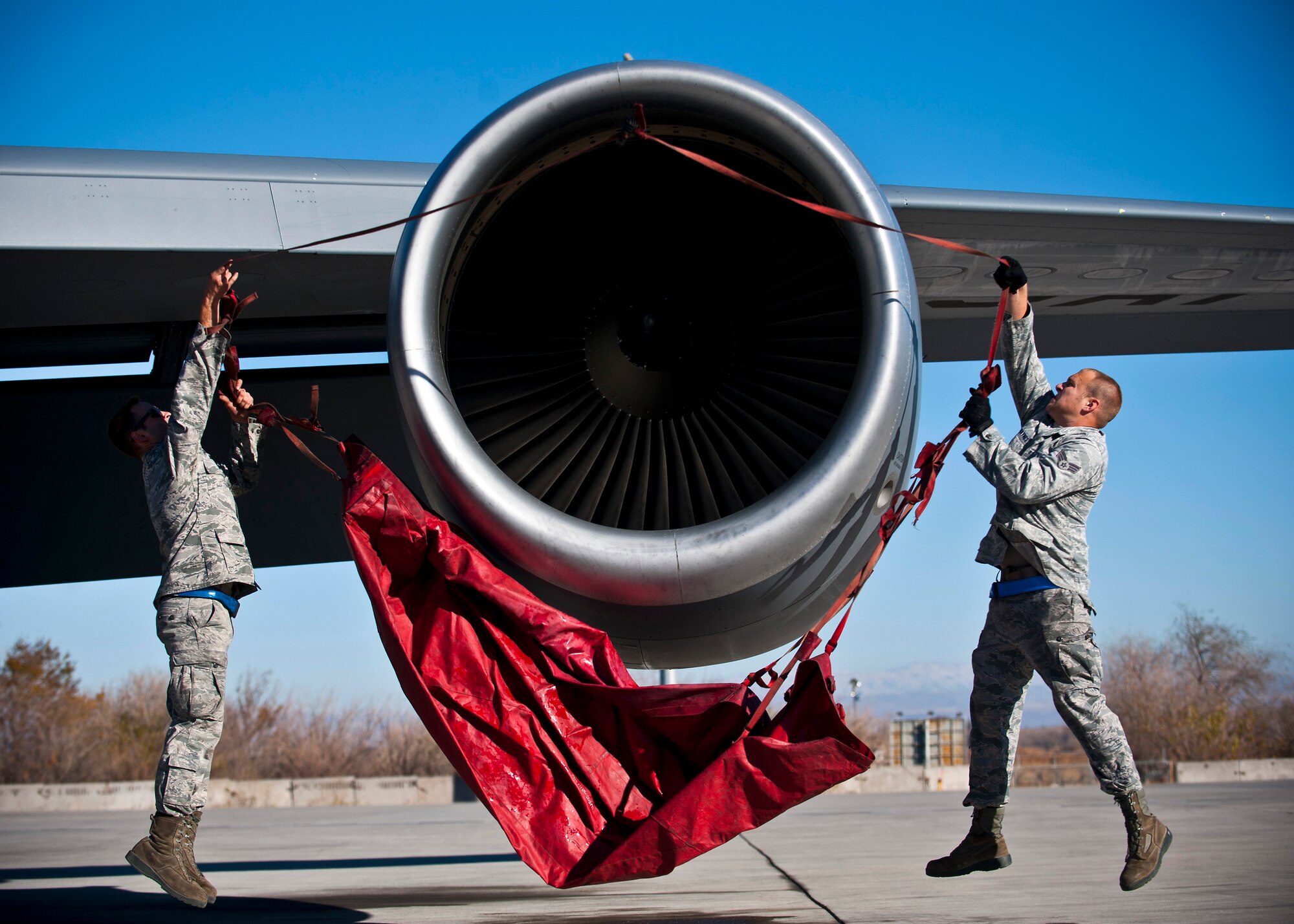 Left, Airman 1st Class Charles Melendez and Senior Airman Cody Haynes throw a protective cover over a KC-135 Stratotanker engine at the Transit Center at Manas, Kyrgyzstan, Nov. 8, 2012. The cover protects the engines from debris or foreign objects. Both Melendez and Haynes are 376th Expeditionary Aircraft Maintenance Squadron crew chiefs who are deployed from Fairchild Air Force Base, Wash. Melendez is a native of San Juan, Puerto Rico and Haynes is a native of Woodbridge, Va. (U.S. Air Force photo/Senior Airman Brett Clashman)