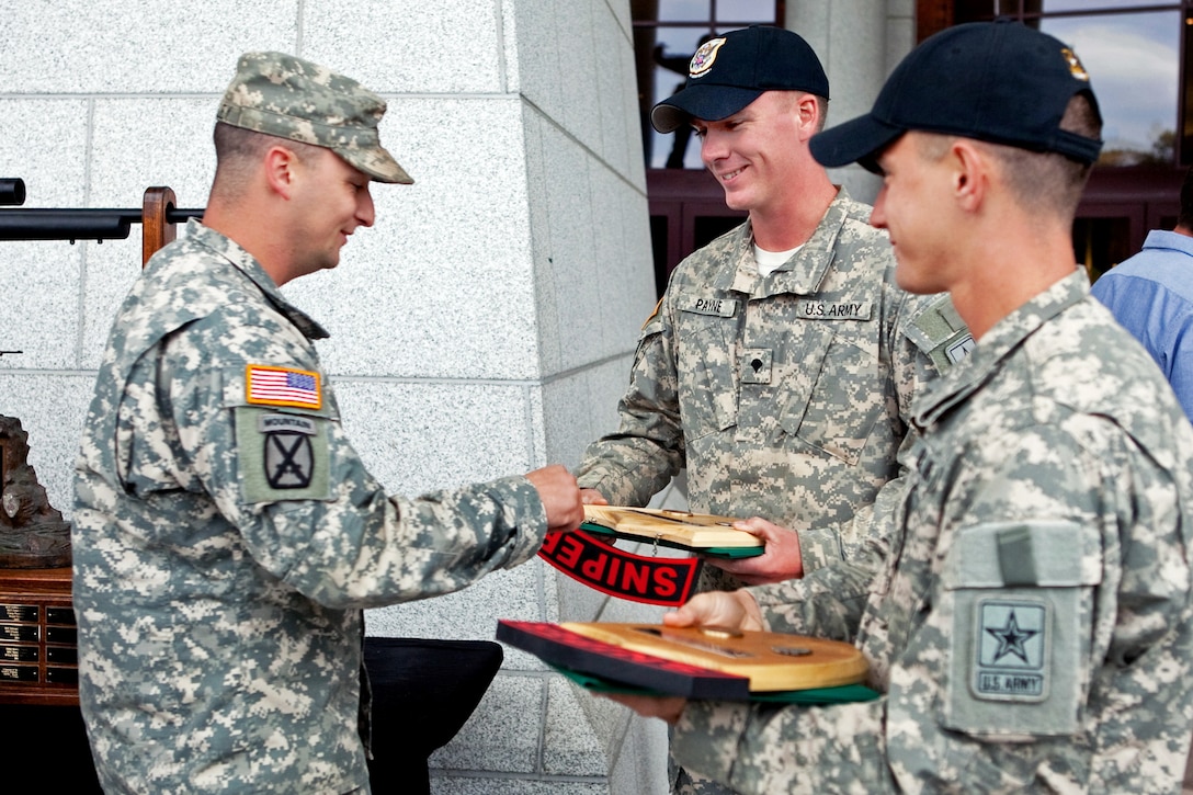 Army Sgt. 1st Class Rodney L. Medley, left, presents a plaque to Army Staff Sgt. Daniel Horner, right, and Army Spc. Tyler Payne, center, for their first-place finish in the 2012 International Sniper Competition at the U.S. Army Sniper School on Fort Benning, Ga., Nov. 7, 2012. Horner and Payne, sniper instructors, are assigned to the Army Marksmenship Unit, Fort Benning.