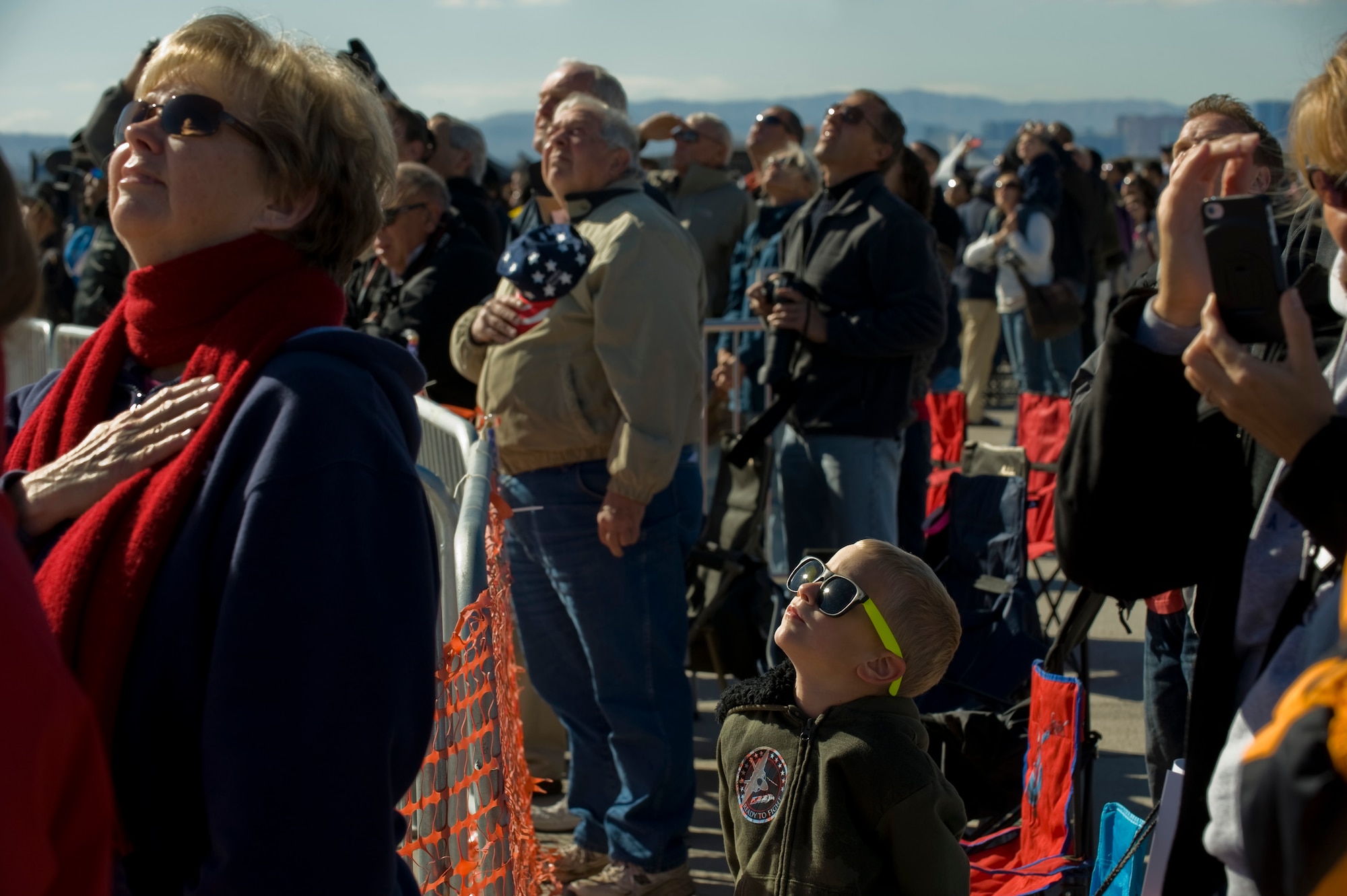 Aviation Nation spectators listen as the national anthem is played during the opening ceremony Nov.10, 2012, at Nellis Air Force Base, Nev. Aviation Nation celebrates 71 years of airpower in Las Vegas and the Air Force's accomplishments in air, space and cyberspace. (U.S. Air Force photo by Staff Sgt. William P. Coleman) 
  

