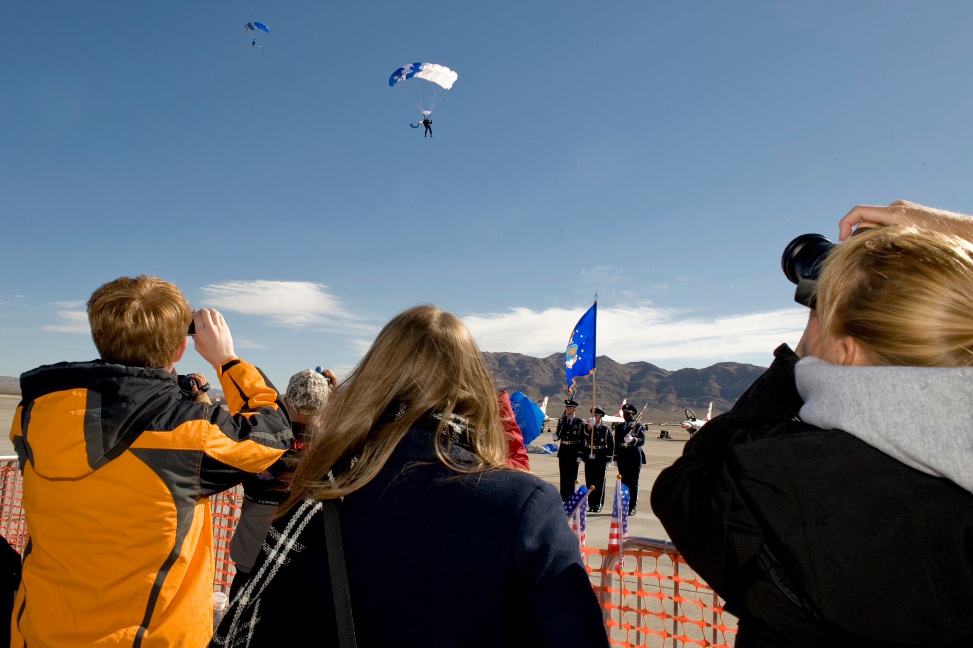 Spectators watch as the U.S. Air Force Academy's Wings of Blue Parachute Team descend from an 8,000 foot jump during Aviation Nation Nov.10, 2012, at Nellis Air Force Base, Nev. The Wings of Blue demonstration team is composed of United States Air Force Academy cadet jumpers and 98th Flying Training Squadron staff members who perform globally on a regular basis. (U.S. Air Force photo by Staff Sgt. William P. Coleman) 
  

