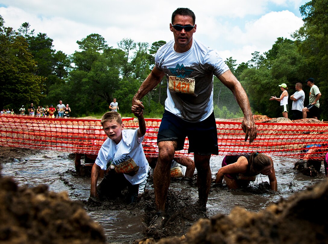 Lt. Col. Jeff Gates, helps his 11-year-old son, Nathaniel, through the first water obstacle May 19 at the Emerald Coast MudRun for Orphans in Niceville Fla.  Active-duty and reserve service members from Duke, Hurlburt Field, Eglin and more came out to get dirty in either the morning or afternoon 5K challenges.  (U.S. Air Force photo/Tech. Sgt. Samuel King Jr.)