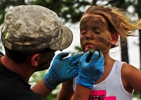 A specialist transforms 7-year-old Kayiah into a camouflaged Army Ranger at the 6th Ranger Training Battalion’s annual open house event, May 12 at Camp Rudder. The event was a chance for the public to learn how Rangers train and operate. The event displays showed dive equipment, weapons, a reptile zoo and zodiac boats among others. The demonstrations showed off hand-to-hand combat, a parachute jump, a down-pilot scenario and others. (U.S. Air Force photo/Tech. Sgt. Samuel King Jr.)