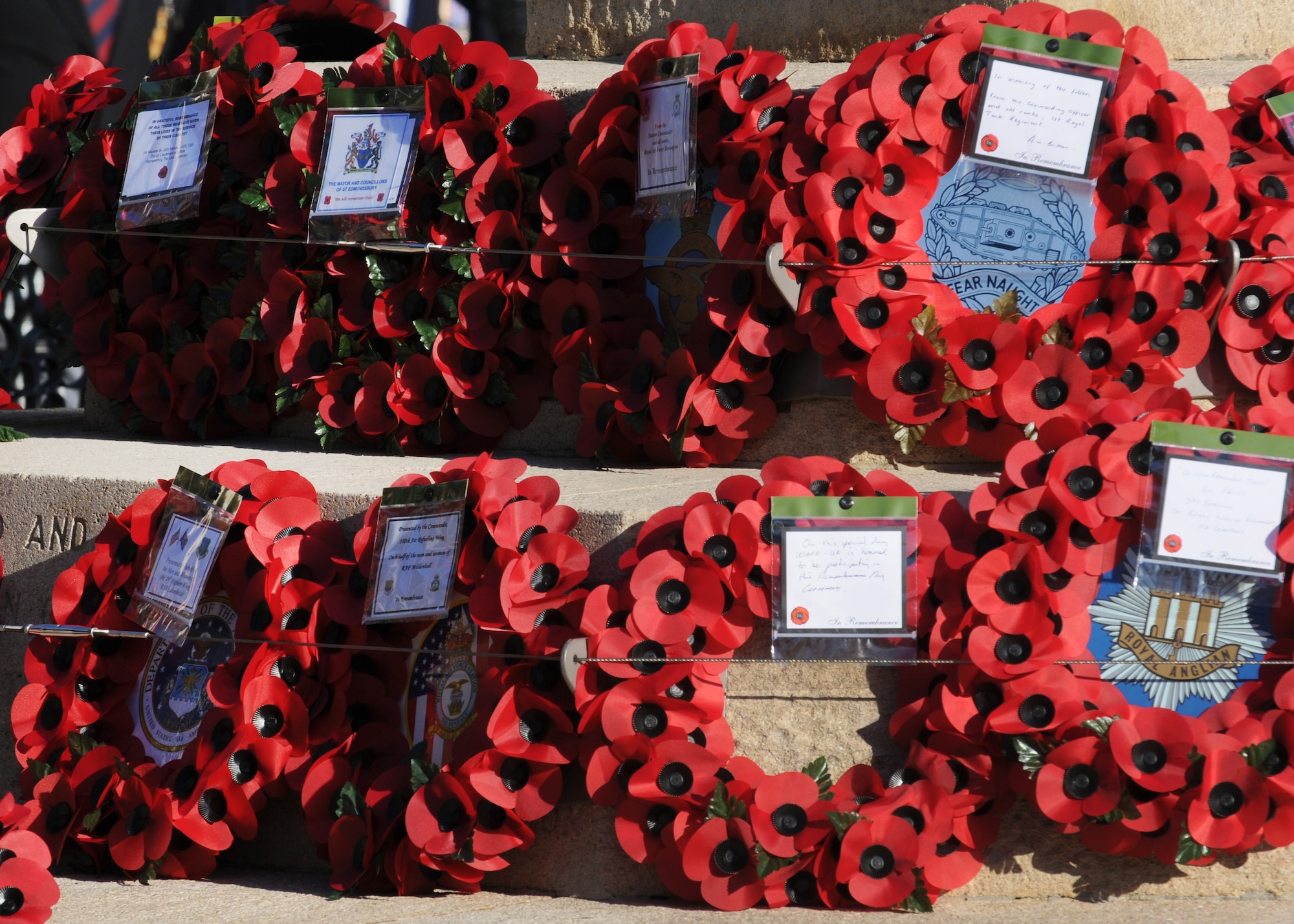 Poppy wreaths rest against the base of a war memorial during a Remembrance Day ceremony Nov. 11, 2012, in Bury St. Edmunds, England.  The poppy was chosen as the symbol of remembrance because many British soldiers lost their lives in the poppy fields of Flanders, Belgium, during WWI. (U.S. Air Force photo by Staff Sgt. Tabitha M. Lee/Released)