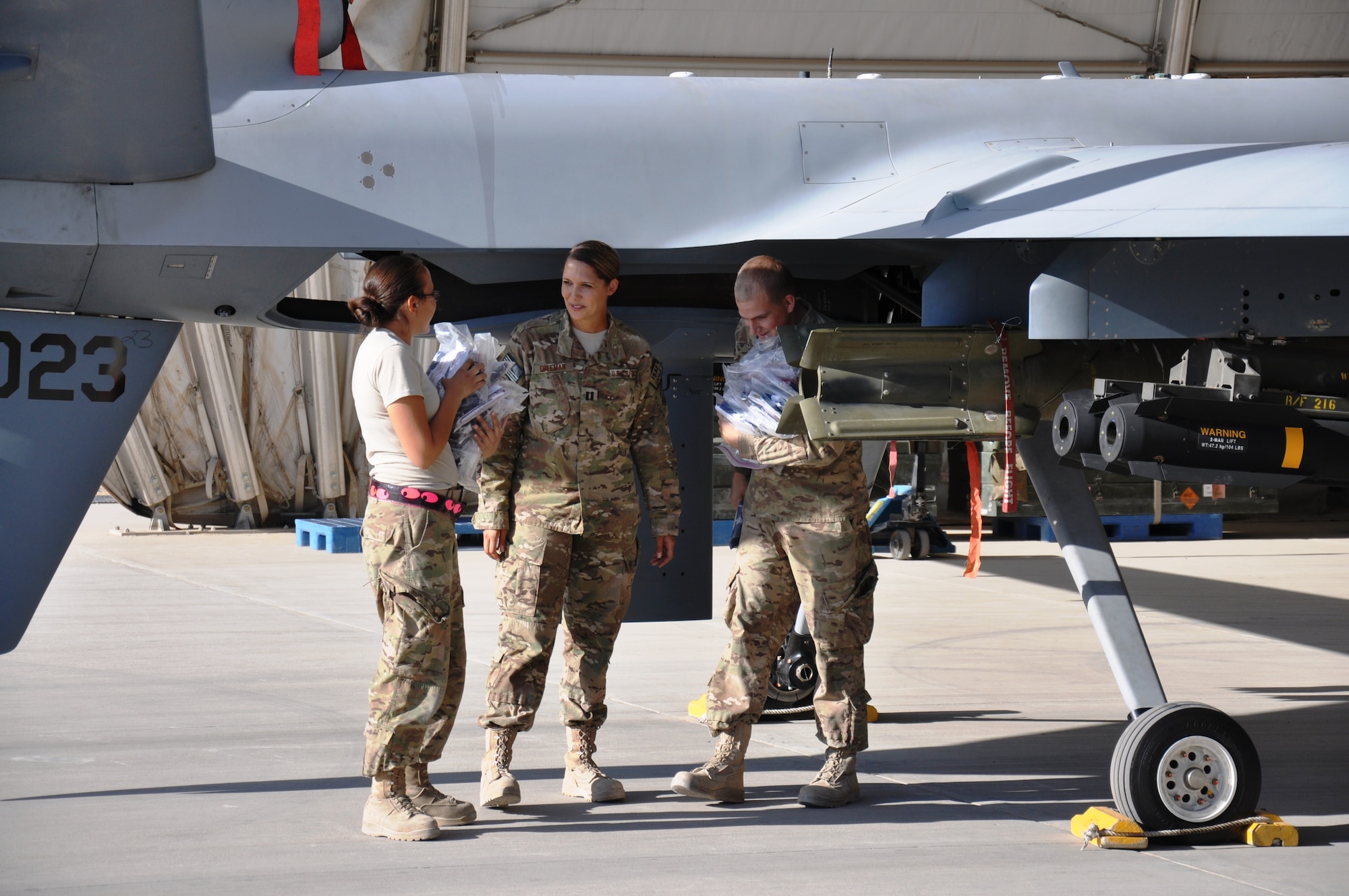 Staff Sgt. Alejandra Uribe and Airman First Class Tyler Rude, weapons troops with the MQ-9 Reaper Aircraft Maintenance Unit, remove flags from the aircraft after a mission on Nov. 3, 2012. The unit creates certificates to go with the flags, certifying that they have been flown in combat. The Airmen are talking to Capt. Lindsay Freeman, officer-in-charge of the AMU. (U.S. Air Force photo/Capt. Tristan Hinderliter) 