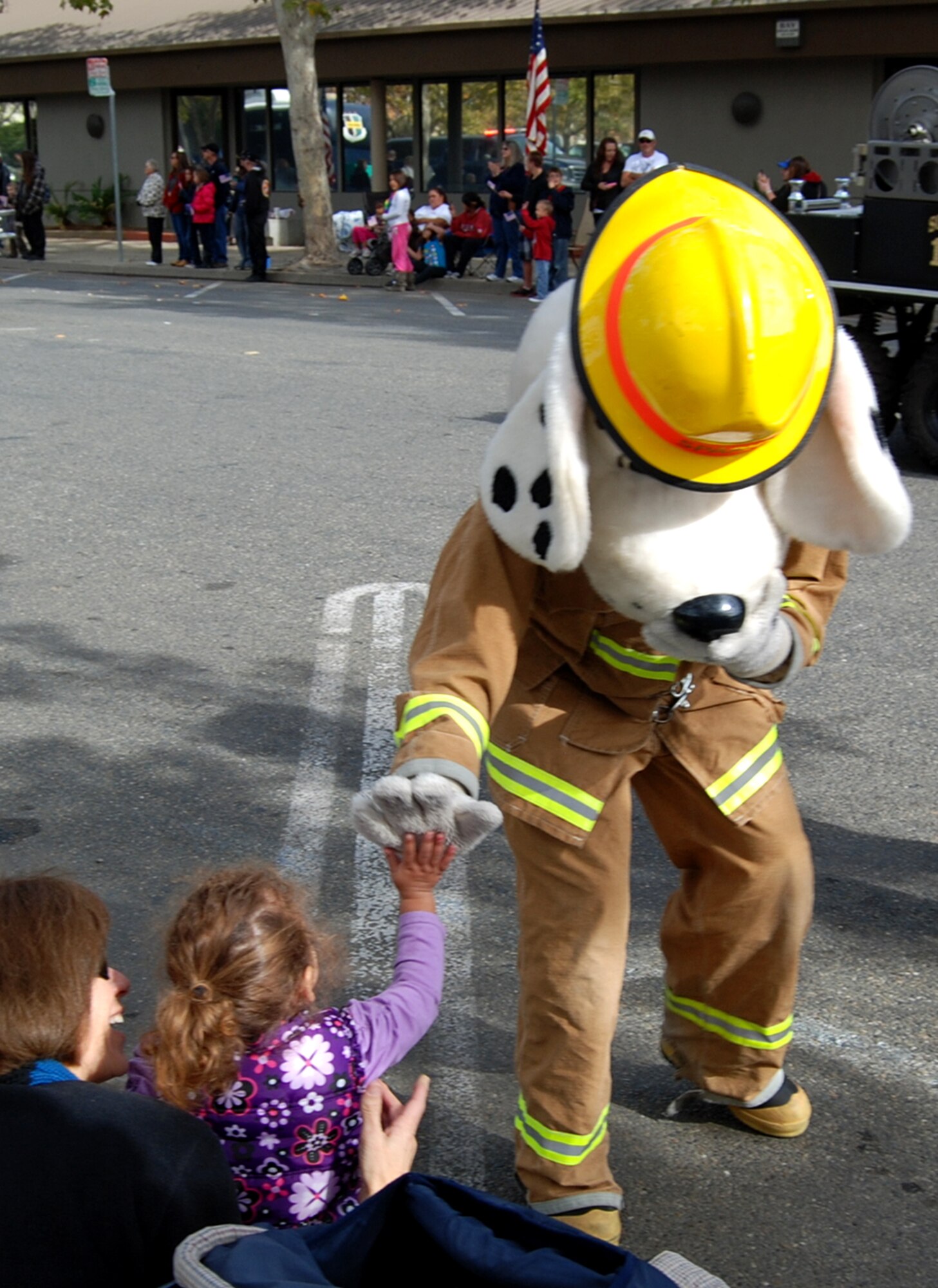 Sparky the Fire Dog gives a high five to a girl sitting along the parade route during the Yuba-Sutter Veterans Day Parade in Marysville, Calif., Nov. 11, 2012. More than 400 Team Beale Airmen participated in the parade. (U.S. Air Force photo by Capt. Brian Wagner/Released)