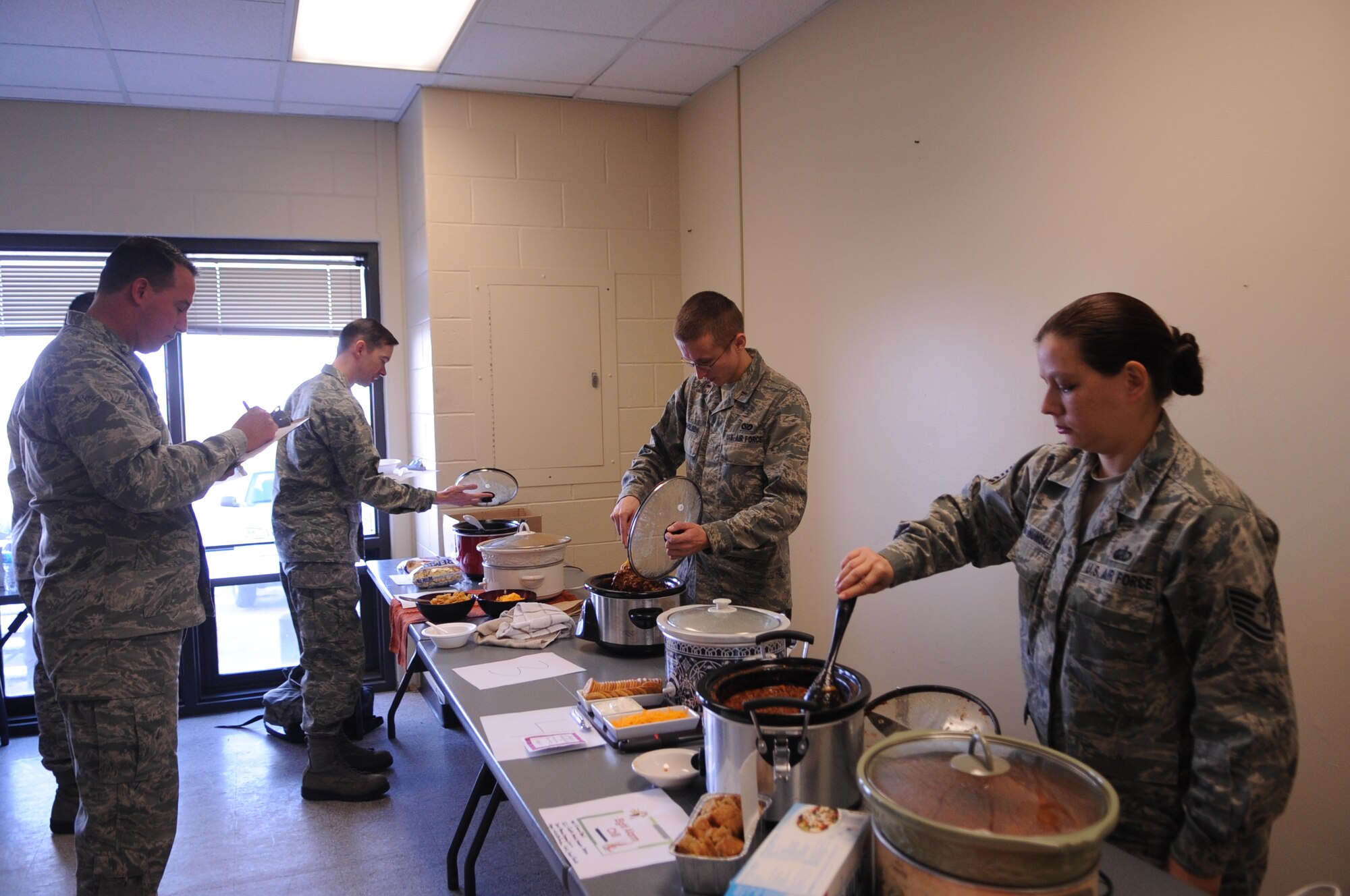 Contestants in the Wing Safety Day Chili Cook-off prepare their entries for Col. Tim Bush, 319th Air Base Wing commander, left, during Wing Safety Day on Grand Forks Air Force Base, N.D., on Nov. 5, 2012. Wing Safety Day featured speakers from the base and local community to promote safe practices for the coming winter. (U.S. Air Force photo/Staff Sgt. Amanda N. Grabiec)