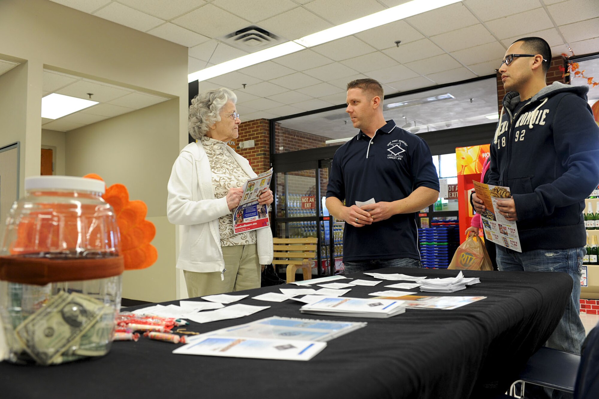 U.S. Air Force Master Sgt. James Kaufman, 438th Supply Chain Operation Squadron first sergeant (center) and Staff Sgt. Eric Perez, 438th SCOS F-16 weapons system management flight supervisor, inform Audra Caldwell how to donate to the Operation Warmheart organization at the Base Exchange, Langley Air Force Base, Va., Nov. 9, 2012. Operation Warmheart is an organization run by first sergeants to help Airmen in need, especially during the holidays. (U.S. Air Force photo by Staff Sgt. Ashley Hawkins/Released)