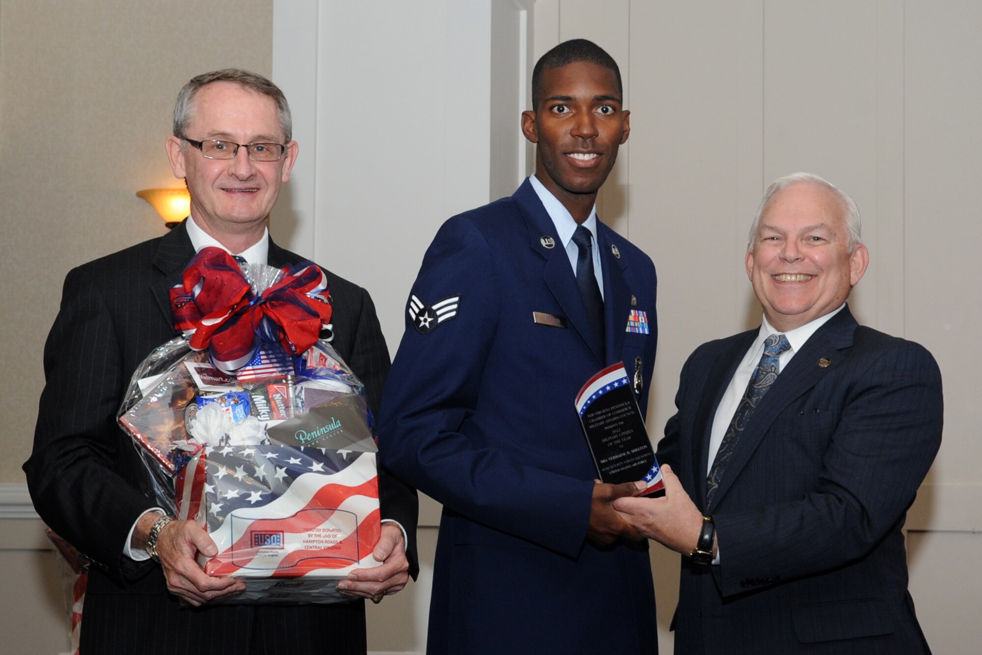 John Gately (left), Virginia Peninsula Chambers of Commerce military affairs council co-chair, Mike Kuhns (right), president and chief executive officer of VPCC, presents a Military Citizen of the Year award to U.S. Air Force Senior Airman Vermaine Shelton (center), 633rd Security Forces Squadron community policing, during a military recognition luncheon at Newport News, Va., Nov. 13, 2012. Shelton is part of a 12-person community policing team, ensuring protection of 3,100 joint service military residents, and policing efforts for more than 200 square acres and 1,200 housing units. This event honors local military personnel from each branch for their outstanding contributions to the greater good of the Virginia Peninsula. (U.S. Air Force photo by Senior Airman Racheal E. Watson/Released)