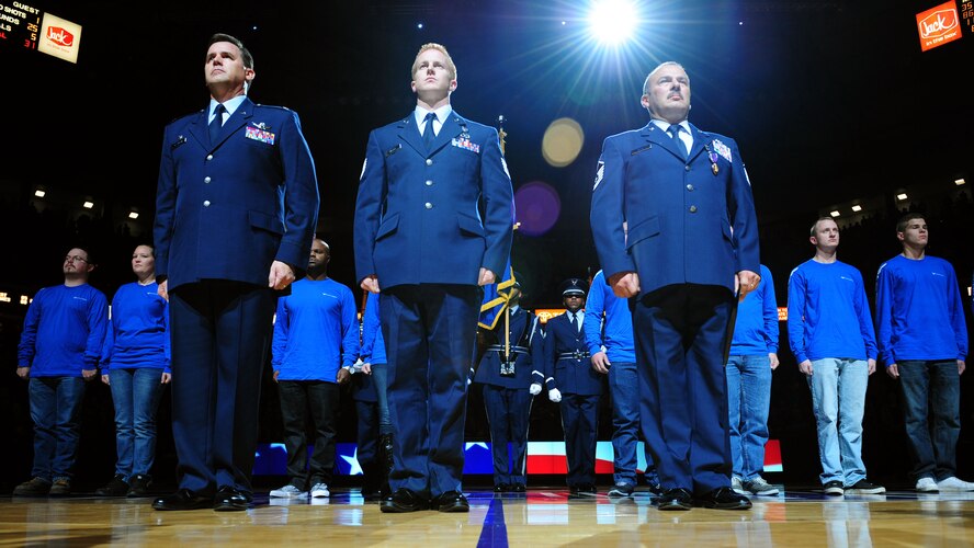 Col. Kevin Cavanagh, 940th Wing commander, Tech. Sgt. Derek Miller and Master Sgt. Pedro Villa stand at attention during a recognition ceremony at a Sacramento Kings game in Sacramento, Calif., Nov. 9, 2012. Miller was presented an Air Force Combat Action Medal and Villa received a Purple Heart for their actions during Operation Enduring Freedom. (U.S. Air Force photo by Senior Airman Shawn Nickel/Released)