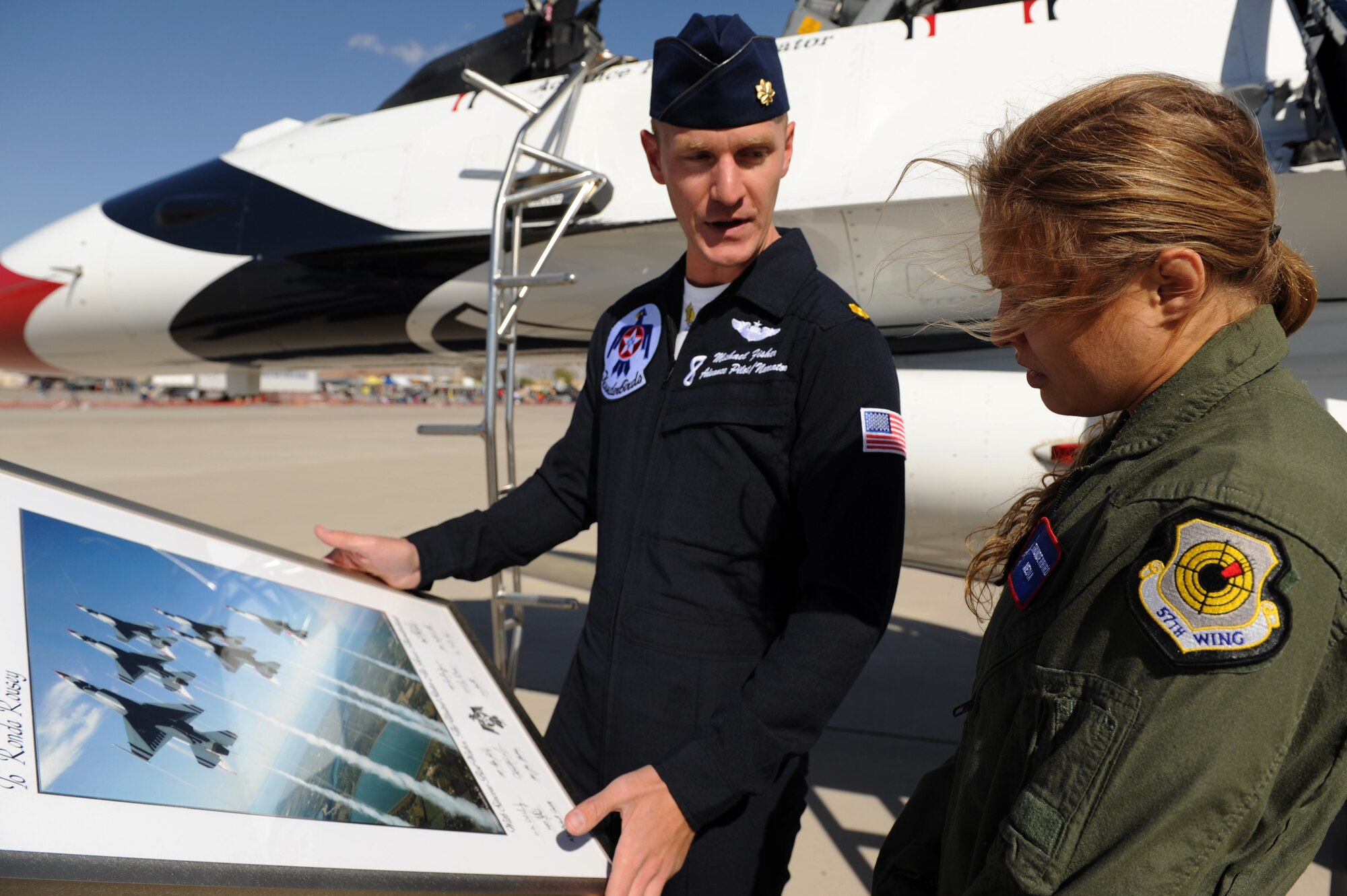 Major Michael Fisher, Thunderbird 8, Advance Pilot/Narrator, presents mixed martial artist champion, Ronda Rousey, a commemorative lithograph after her flight in the F-16 Fighting Falcon, at Nellis Air Force Base, Nev., Nov. 9, 2012.
(U.S. Air Force photo/Staff Sgt. Larry E. Reid Jr., Released)