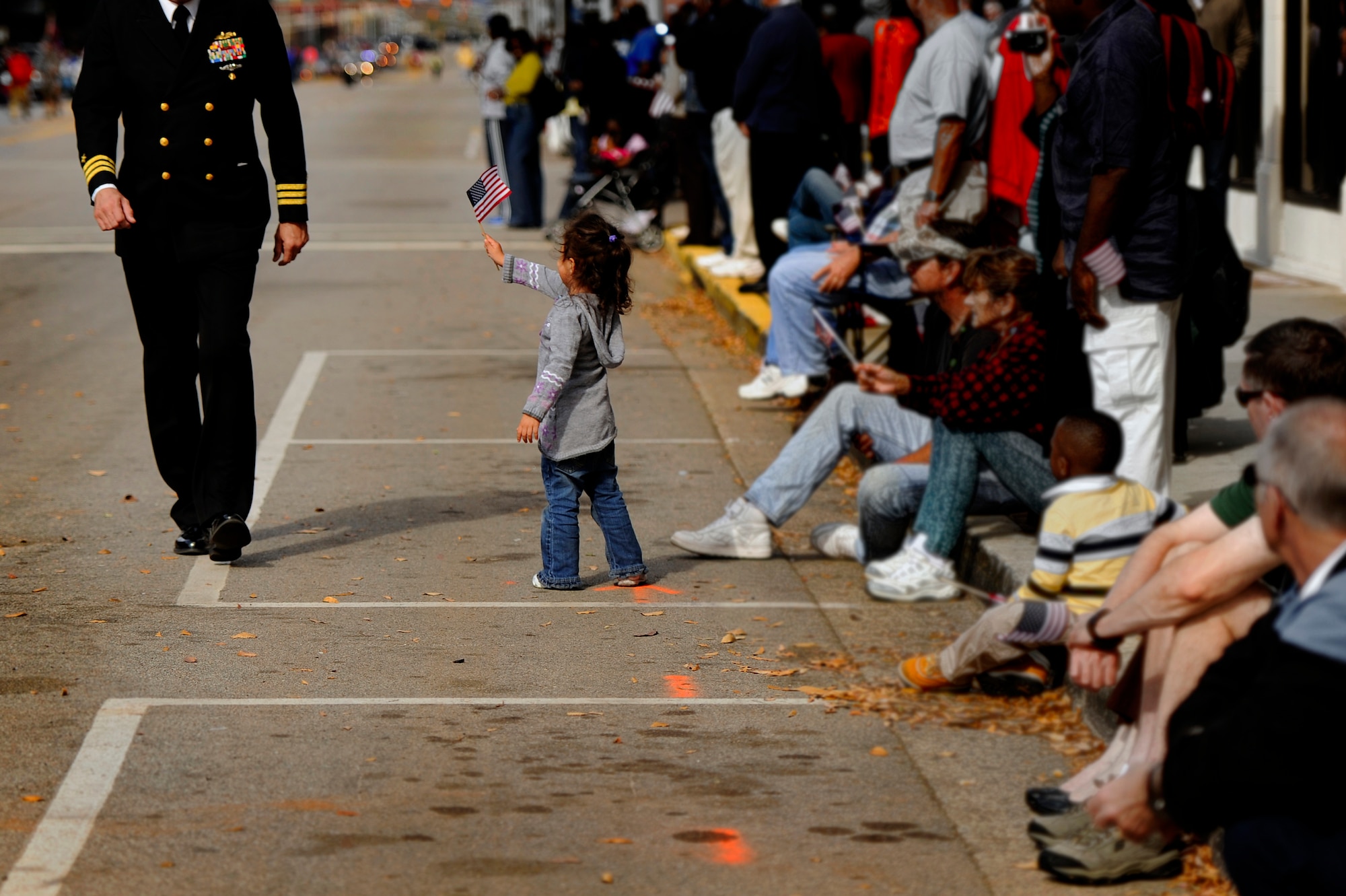 A young girl offers her American flag to a U.S. Navy member as he passes by during a Veterans Day Parade, Nov. 12, 2012, Columbia, S.C. The parade which took place on Sumter Street in the middle of downtown saw hundreds of civilians, veterans, and active-duty military personnel, to include Airmen from Shaw Air Force Base, in attendance. The event was Columbia’s 34th annual Veterans Day Parade. (U.S. Air Force photo by Staff Sgt. Kenny Holston/Released) 