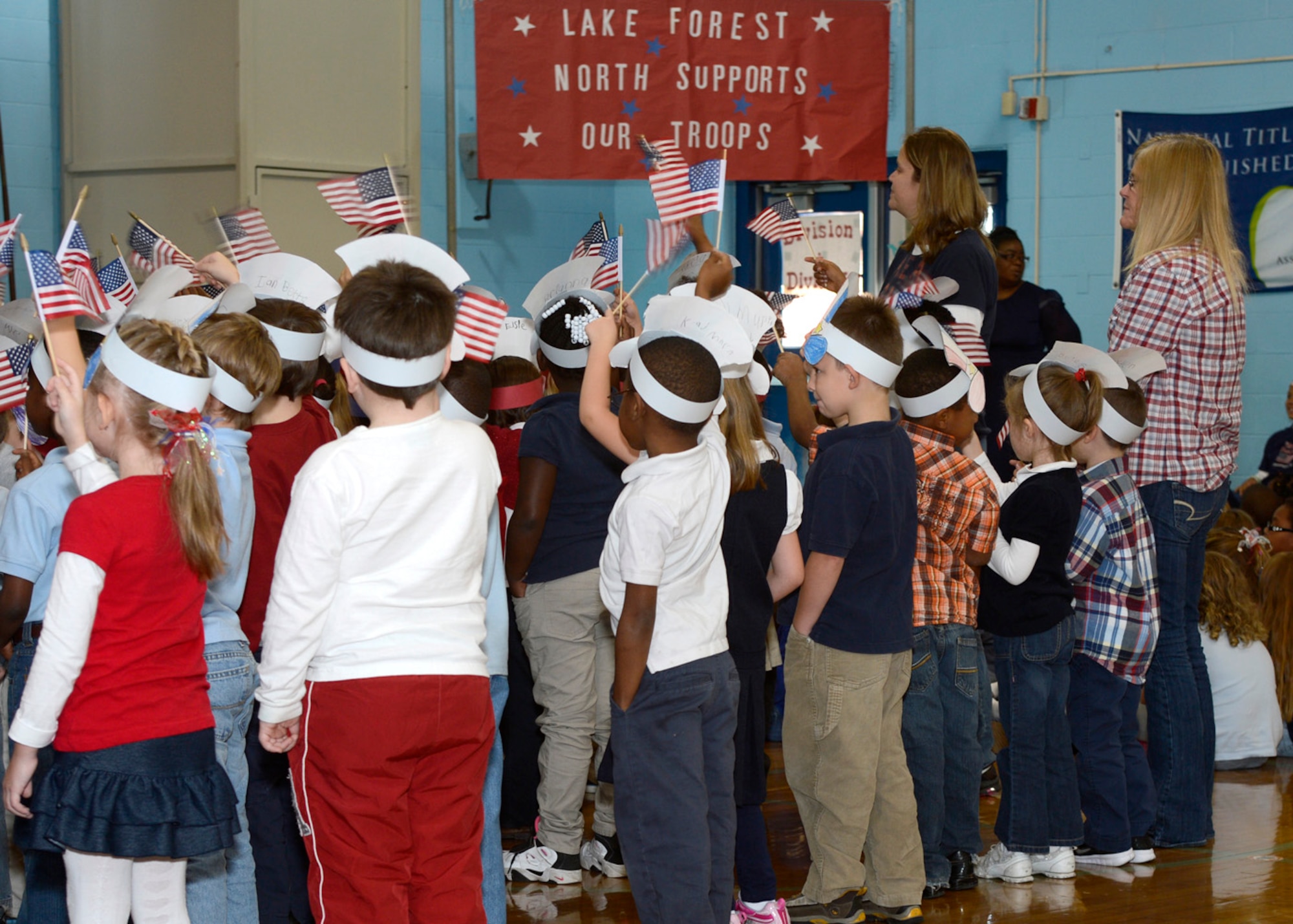 Students and teachers wave U.S. flags as they sing “Grand Old Flag” during a Veteran’s Day celebration Nov. 9, 2012, at Lake Forest North Elementary School in Felton, Del. Service members from Dover Air Force Base, Del., spoke to the students about military service. (U.S. Air Force photo by Tech. Sgt. Chuck Walker)