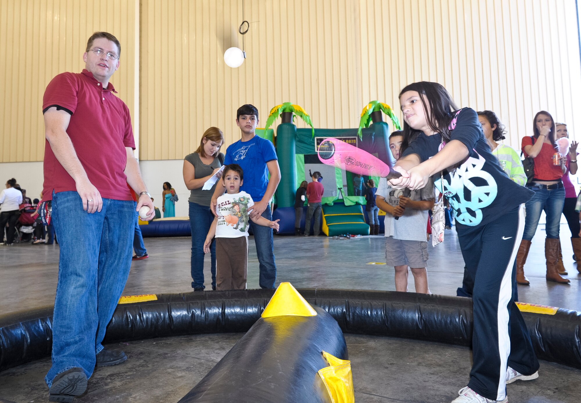 Tech. Sgt. James Cheney, 116th Comptroller Flight, mans the World Games Baseball booth while Jasmine Perez connects with the ball during the 116th and 461st Air Control wings annual Family Day celebration at Robins Air Force Base, Ga., Nov. 3, 2012. This marked the 10th annual Family Day for JSTARS.  The yearly event provides an opportunity to thank families for their support.   (National Guard photo by Master Sgt. Roger Parsons/Released)