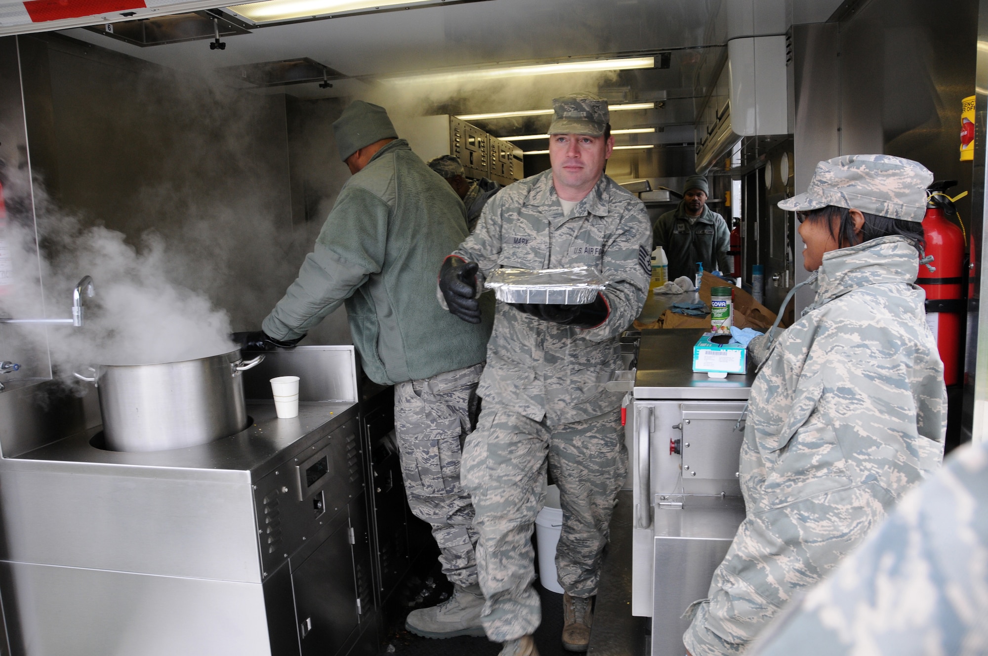 Tech. Sgt Marx from the 113th Force Support Squardon brings hot food to awaiting airman during a new mobile field kitchen during a demonstration at Joint Base Andrews, Md., Nov. 3. The Disaster Relief Mobile Kitchen Trailer  can deploy to natural disaster sites to provide hot meals to relief workers and Airmen working in austere conditions. (U.S. Air force photo by Airman 1st Class Sumena Leslie/Released)