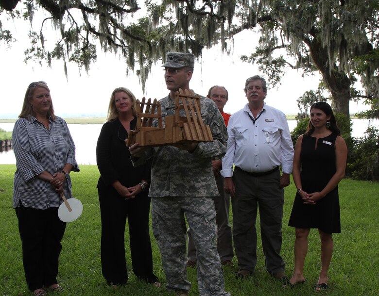 Lt. Col. Chamberlayne and the regulatory team discuss the issued permit with a model of the rice trunks.