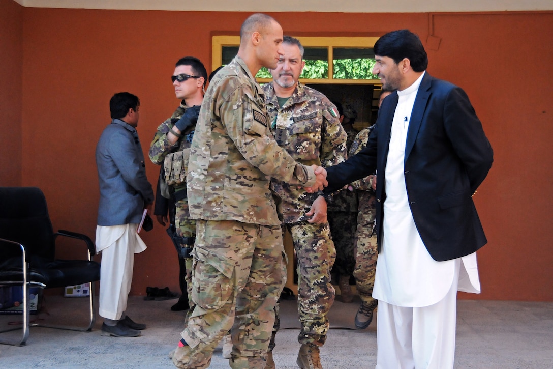 U.S. Navy Cmdr. Louis McCray shakes hands with Dr. Mohammad Akram Khpalwak, governor of Farah province, Afghanistan, while Italian Army Col. Riccardo Cristoni, center, commander, Task Force South, looks on after a key leaders meeting in Farah City, Afghanistan, Nov. 12, 2012. McCray commands Provincial Reconstruction Team Farah.