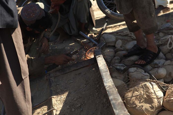 A local villager repairs the front end of the ferry that carries passengers and vehicles across the Helmand River in Sangin, Afghanistan, Nov. 10, 2012. The ferry is one of the few options the local people can use to cross the river.