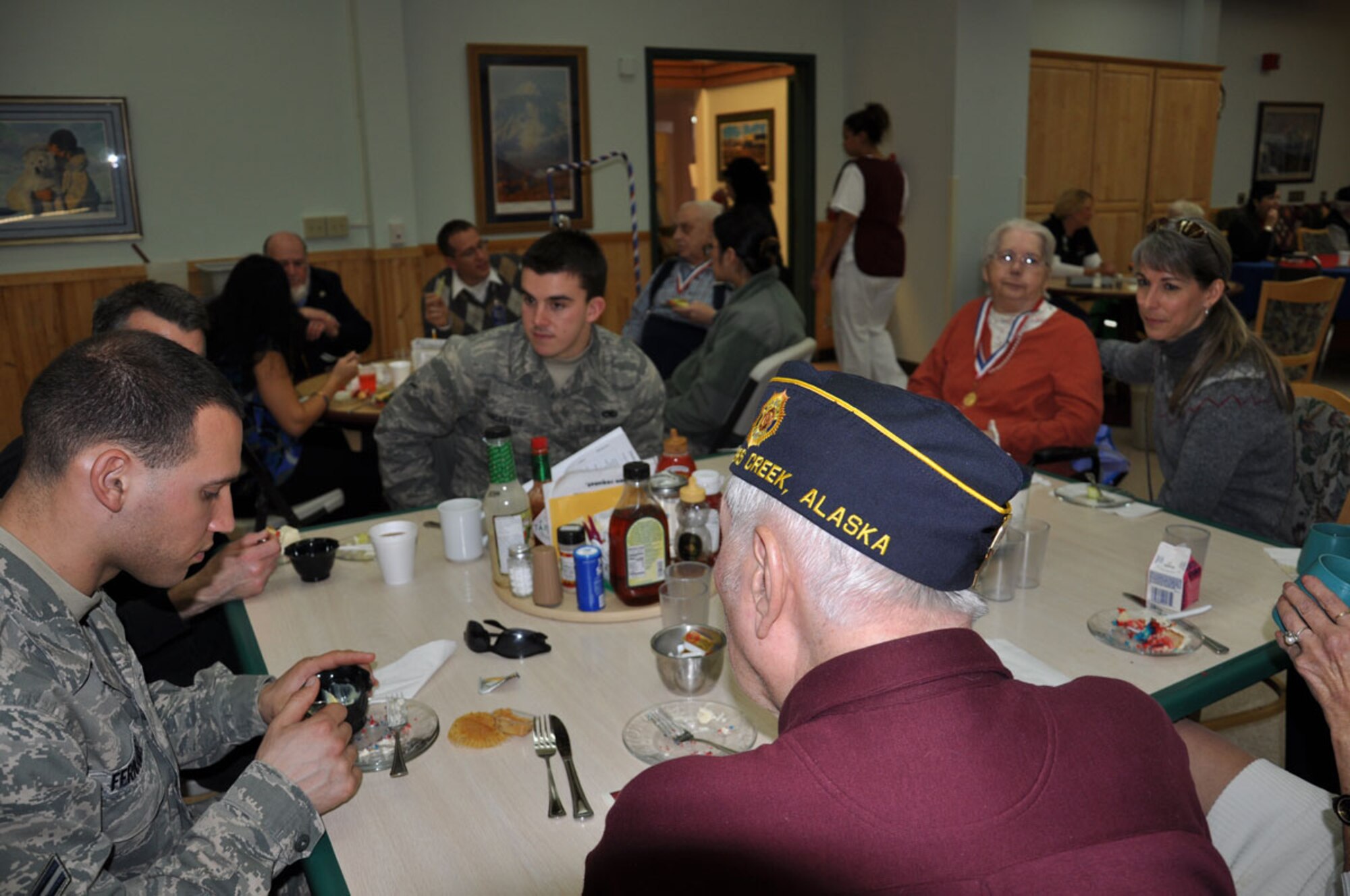 Airmen from JBER’s 525th Fighter Squadron and 3rd Operations Support Squadron spent Veterans Day with veterans who reside at the Alaska Veterans and Pioneers Home in Palmer. Airman Sean Lancaster (center), an aircraft armament specialist, and Airman 1st Class Edgardo Fernandez (far left), both of the 525th FS, visit with veterans after a ceremony which opened in prayer followed by music, the Pledge of Allegiance, and guest speakers delivering messages from military leaders. Fernandez said he really enjoyed spending time with the elderly veterans who had great stories to share.  “There’s so much to learn from them,” he said. (U.S. Air Force photo/Erin Eaton)

