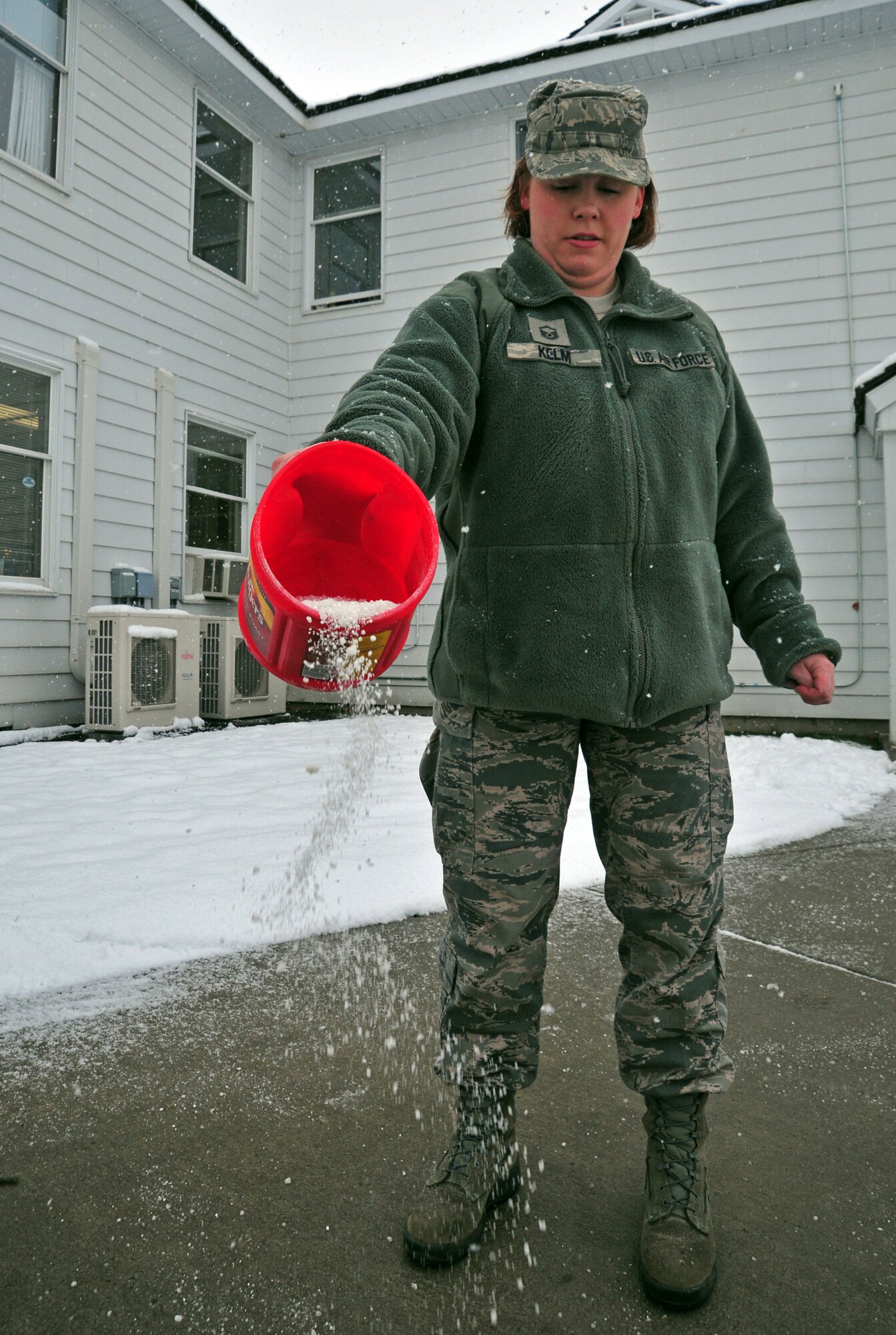 Master Sgt. Bryna Kelm pours salt over the sidewalks around the wing headquarters building at Fairchild Air Force Base Wash., Nov. 9, 2012. The snow depth reached three inches during the morning. Kelm is the military personnel section NCO-in charge with the 141st Force Support Squadron. (U.S. Air Force photo by Airman 1st Class Taylor Curry)