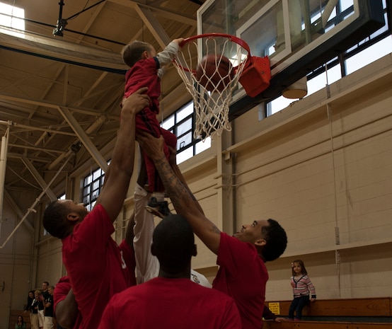 Basketball players from Ohio State help Drew Yon, son of Capt. Richard Yon, 628th Medical Group Bioenvironmental Squadron, dunk during a Hoops from Home Clinic Nov. 8, 2012, at Joint Base Charleston, S.C. Hoops from Home is a non-profit organization providing a basketball camp/clinic experience to children of military families across the world. It provides the children an opportunity to work with players and coaches and highlight the benefits of team sports, physical activity and commitment. (U.S. Air Force photo/Airman 1st Class Ashlee Galloway)