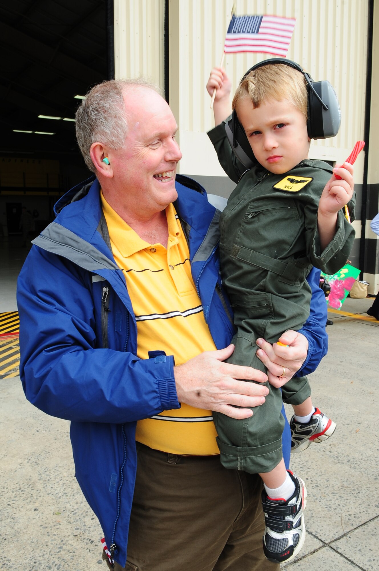 Brad Kemmerer, father-in-law of U.S. Air Force Capt. Aaron Kiser, 336th Fighter Squadron pilot, laughs as Will Kiser, 3, waves an American flag and awaits his dad’s landing on Seymour Johnson Air Force Base, N.C., Nov. 14, 2012. The aircrew returned from a six-month deployment to the Middle East. (U.S. Air Force photo/Airman 1st Class Aubrey White/Released)