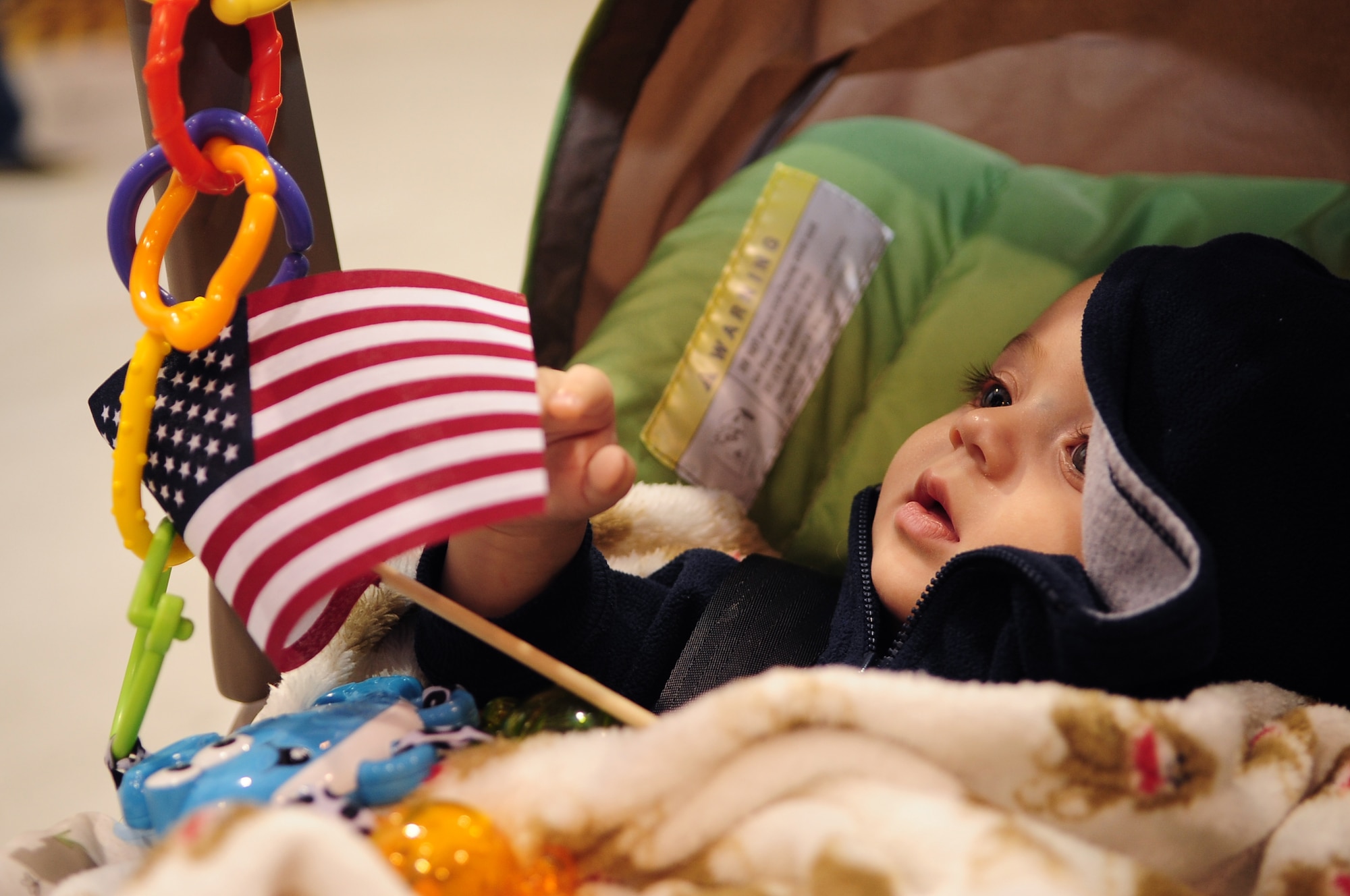 Austin Evans, 6 months, admires an American flag as he awaits the arrival of his father, U.S. Air Force Staff Sgt. Jonathan Evans, 4th Equipment Maintenance Squadron, at a deployment return on Seymour Johnson Air Force Base, N.C., Nov. 14, 2012. Austin was born a week prior to Evans’ departure for a six-month deployment to the Middle East. (U.S. Air Force photo/Airman 1st Class Aubrey White/Released)