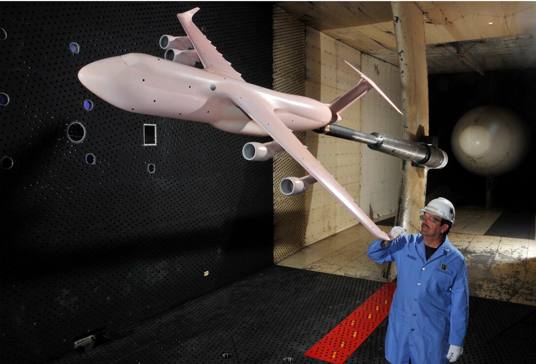 Jim Crawford, an outside machinist with the Aerospace Testing Alliance (ATA) Flight Systems Operation and Maintenance branch, inspects a winglet on the wingtip of the C-5M Super Galaxy model during a break in testing in Arnold Engineering Development Complex’s (AEDC) 16-foot Transonic Wind Tunnel (16T). The model is a pink color as a result of AEDC’s application of Pressure Sensitive Paint (PSP) to it before the test was conducted. (Photo by Rick Goodfriend)
