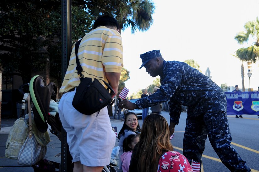 Capt. Mark Glover, Space and Naval Warfare Systems Center Atlantic commanding officer, passes out American flags during the Veterans Day Parade Nov. 10, 2012, in Charleston, S.C. More than a hundred Airmen and Sailors from Joint Base Charleston marched in the parade, which traveled through the streets of historic downtown Charleston. The parade kicked off with the playing of the National Anthem and a fly-over by a JB Charleston C-17 aircraft. The parade was sponsored by the Ralph H. Johnson VA Medical Center and featured historic military vehicles, motorcycle groups and veterans’ service organization floats. (U.S. Air Force photo/Staff Sgt. Rasheen Douglas)