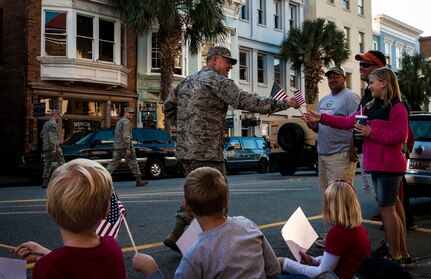 Col. Richard McComb, Joint Base Charleston commander, passes out flags to civilians and veterans during the Veterans Day Parade Nov. 10, 2012, in Charleston, S.C. More than a hundred Airmen and Sailors from JB Charleston marched in the parade, which traveled through the streets of historic downtown Charleston. (U.S. Air Force photo/ Senior Airman Dennis Sloan)
