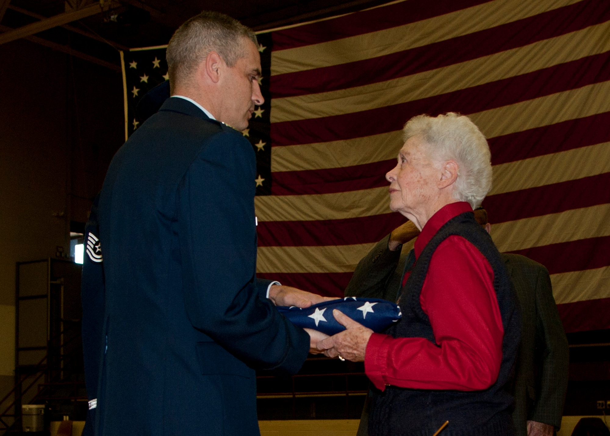VERNON, Texas – Col. Ted A. Detwiler, 97th Operations Group commander, hands Peggy S. Harris, a World War II widow, an American flag during a Vernon High School assembly held to honor U.S. military veterans, Nov. 12, 2012. Peggy’s husband, 1st Lt. Billie D. Harris, was flying a mission over Nazi-occupied France when his plane was shot down and crashed into the woods near a small town in Normandy. He never returned home. Peggy was on a 60-year journey to find answers to her husband’s whereabouts. (U.S. Air Force photo by Airman 1st Class Klynne Pearl Serrano / Released)