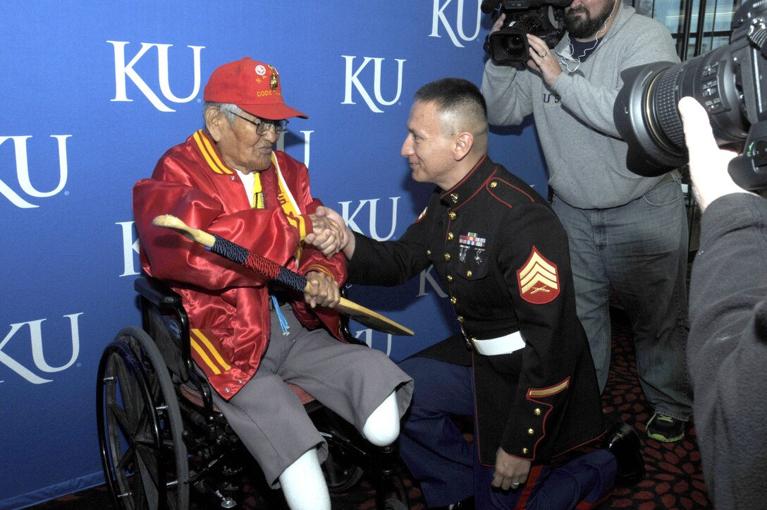 Sgt. Robert Tenfingers, a native Sioux Indian from Pine Ridge, S.D., presents Cpl. Chester Nez, 91, the last survivor of the original 29 World War II Navajo Code Talkers, with a paddle adorned with an inlaid unit coin and plaque. Nez received a Bachelor of Fine Arts degree from Kansas University during a ceremony on Monday. Tenfingers is a program specialist with Recruiting Station Kansas City in Kansas City, Mo. The Officer Selection Officer from RS Kansas City and Marines from the 9th Marine Corps District also attended the ceremony and presented Cpl. Nez with a plaque and certificate from the 9th MCD Commanding Officer.