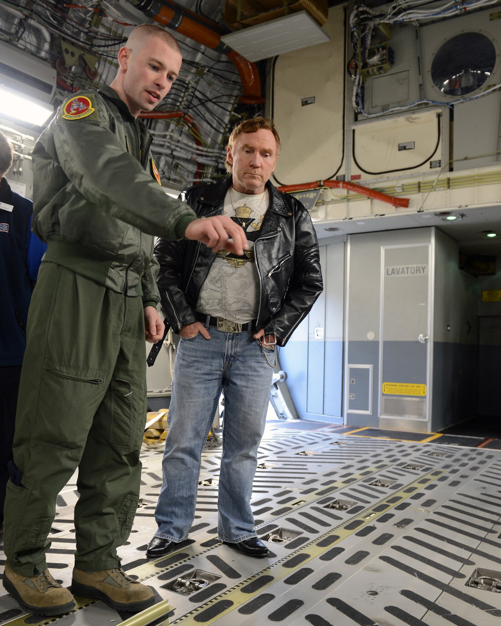 Staff Sgt. John Blanton (left), 10th Airlift Squadron loadmaster, shows Danny Bonaduce, local radio host for KZOK channel 102.5 FM and former child actor, how equipment is loaded and strapped onto a C-17 Globemaster III aircraft Nov. 15, 2012 at Joint Base Lewis-McChord, Wash. Bonaduce was on McChord Field as part of a morale visit in which he stopped by the passenger terminal to wish more than 200 Soldiers a fond farewell before they left for a deployment. (U.S. Air Force photo/Staff Sgt. Sean Tobin)