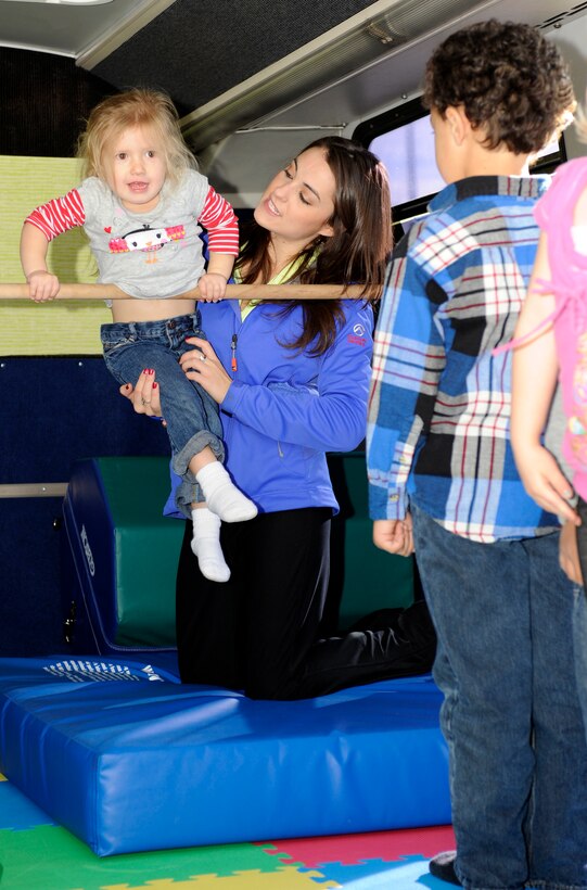 Katie Welch, Tumbling Tots instructor, helps Alena Bank, 3, balance on a horizontal bar inside the Tumbling Tots Tumble Bus during a class on Ellsworth Air Force Base, S.D., Nov. 7, 2012. Welch, who has been involved with gymnastics for the majority of her life, said she enjoys helping children discover the joy of the sport. (U.S. Air Force photo by Airman Ashley J. Woolridge/Released)