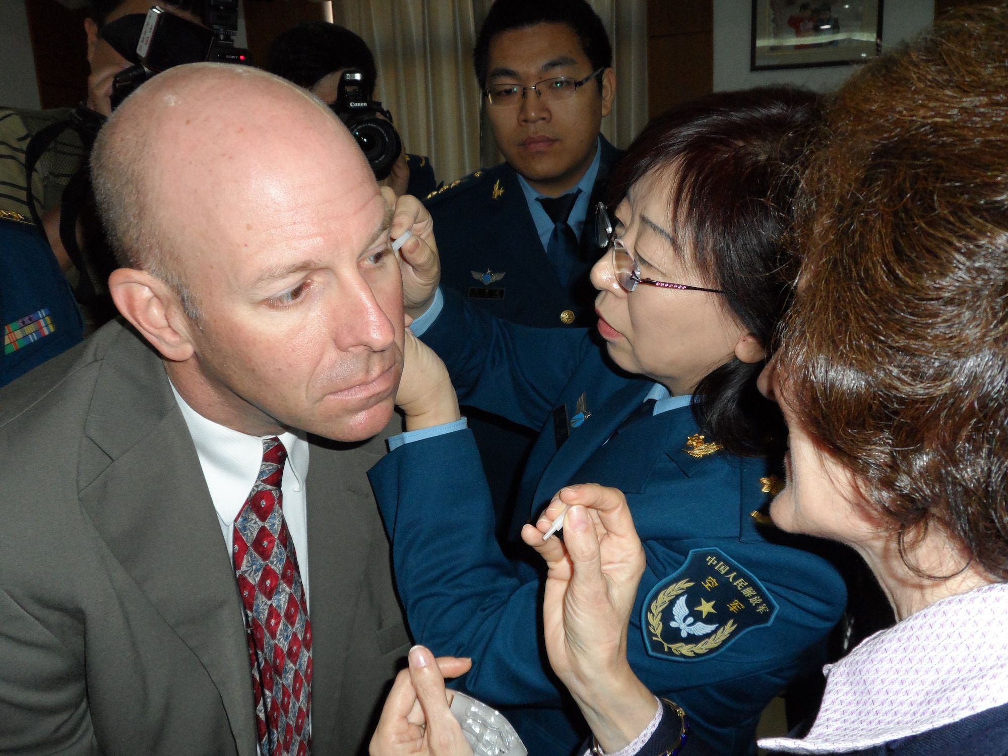 China's People Liberation Army Acupuncturist Huang Xiaojie, pierces the ear of Lt. Col. Greg Sweitzer, Pacific Air Forces Clinical Quality and Innovation chief, with an acupuncture needle under the guidance of Col. Arnyce Pock, Uniformed Services University of the Health Sciences Curriculum Development director, Oct. 23, 2012 at Beijing, China. At the invitation of China's PLA, U.S. Air Force medical physicians, alongside their Chinese military and civilian counterparts, conducted the first-ever Medical Acupuncture Subject Matter Expert Exchange in Beijing Oct. 21-27, 2012. (U.S. Air Force courtesy photo)

