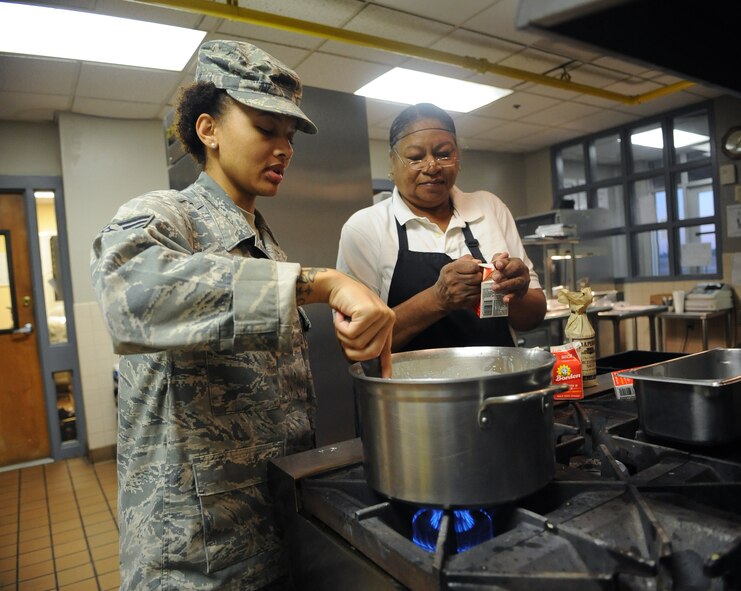 Senior Airman Ashly Williams, 2nd Force Support Squadron food services journeyman, stirs a pot of gravy as Mary O'Neal, 2 FSS Touch and Go Flight Kitchen shift supervisor, opens a carton of milk on Barksdale Air Force Base, La., Nov. 15. The flight kitchen serves breakfast from 6 a.m. to 8 a.m., lunch is served from 11 a.m. to 1:30 p.m. and dinner is served from 3:30 p.m. to 7 p.m. After dinner, the flight kitchen's dining room is closed but Airmen are still able to order box meals from the pick-up window. (U.S. Air Force photo/Senior Airman Micaiah Anthony)(RELEASED)